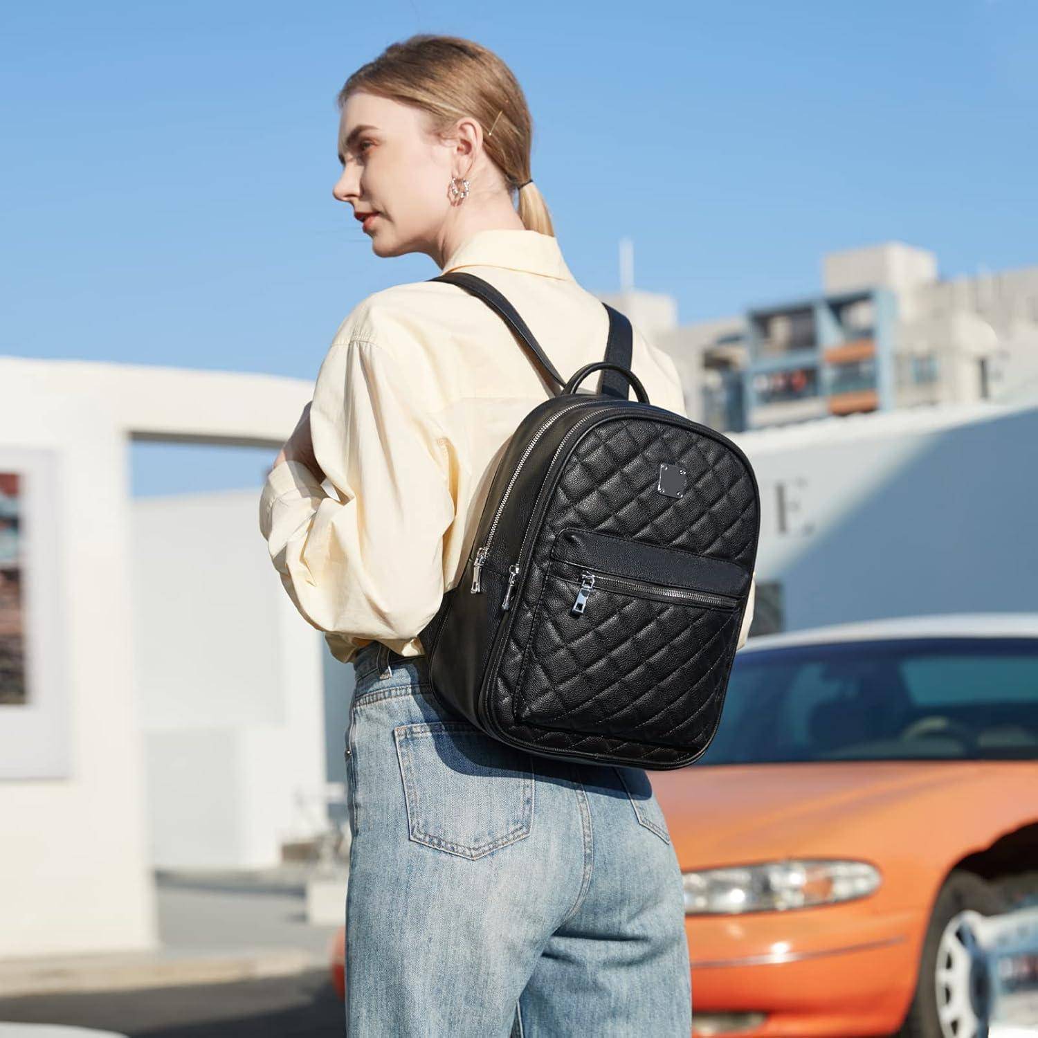 Eine Person in einem cremefarbenen Hemd und Jeans steht im Freien und trägt einen schwarzen gesteppten Rucksack, mit einem verschwommenen urbanen Hintergrund.