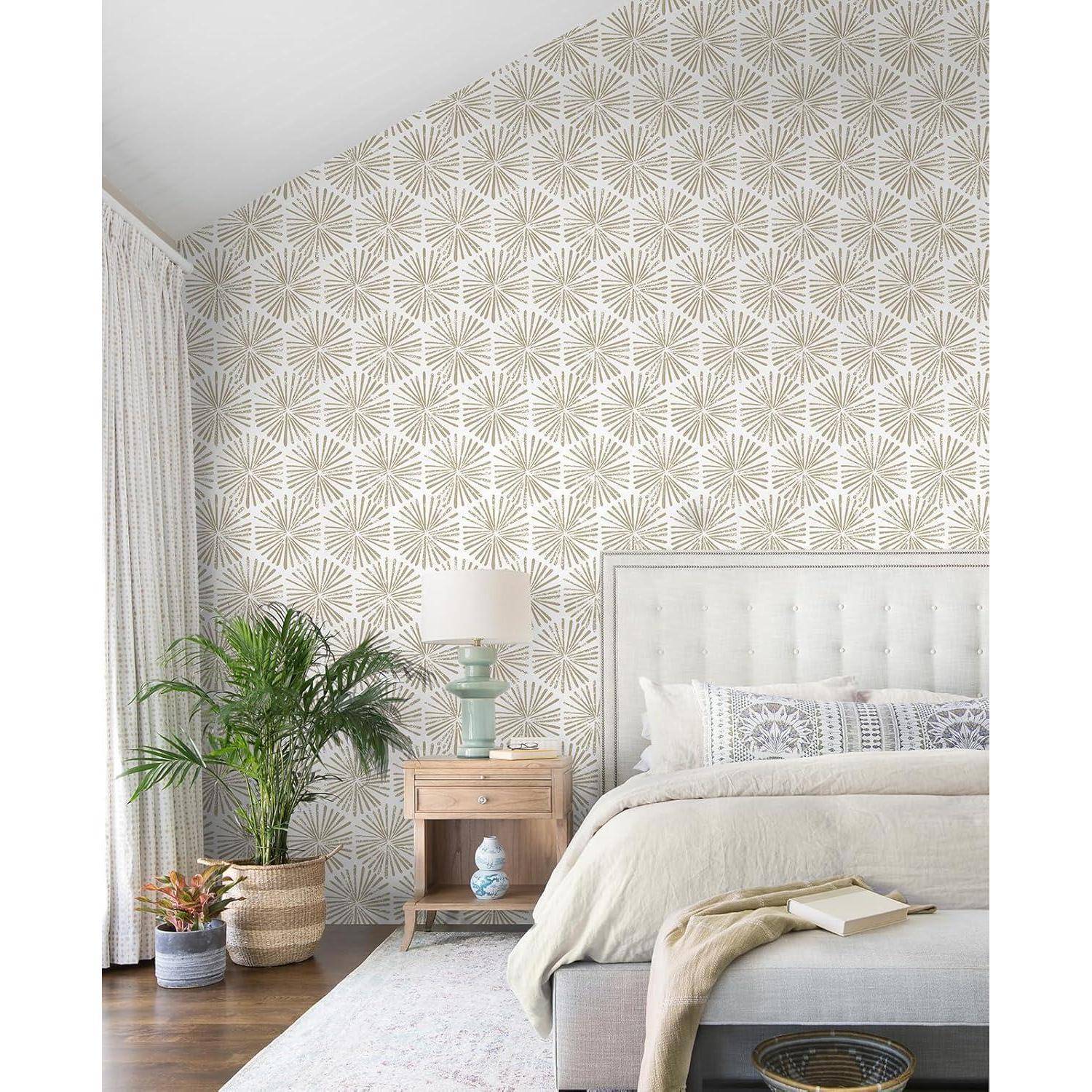 Schlafzimmer mit gemusterter Tapete, Bett mit neutraler Bettwäsche, Nachttisch mit einer Lampe, Pflanze und einem Korb auf dem Boden, helle Gardinen.