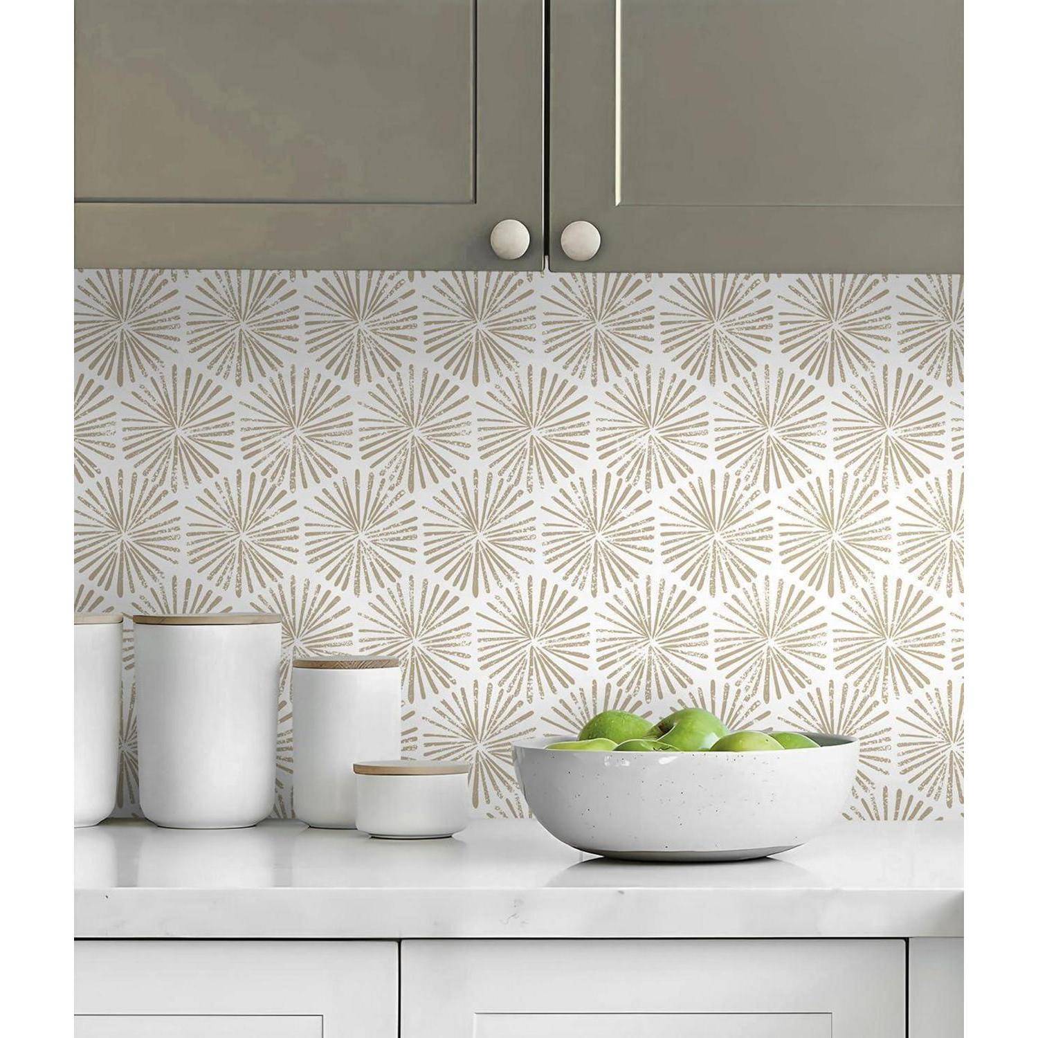 Eine Küchenarbeitsplatte mit weißen Schränken und einer dekorativen Rückwand mit einem beigen geometrischen Muster. Eine Schüssel mit grünen Äpfeln steht auf der Arbeitsplatte.