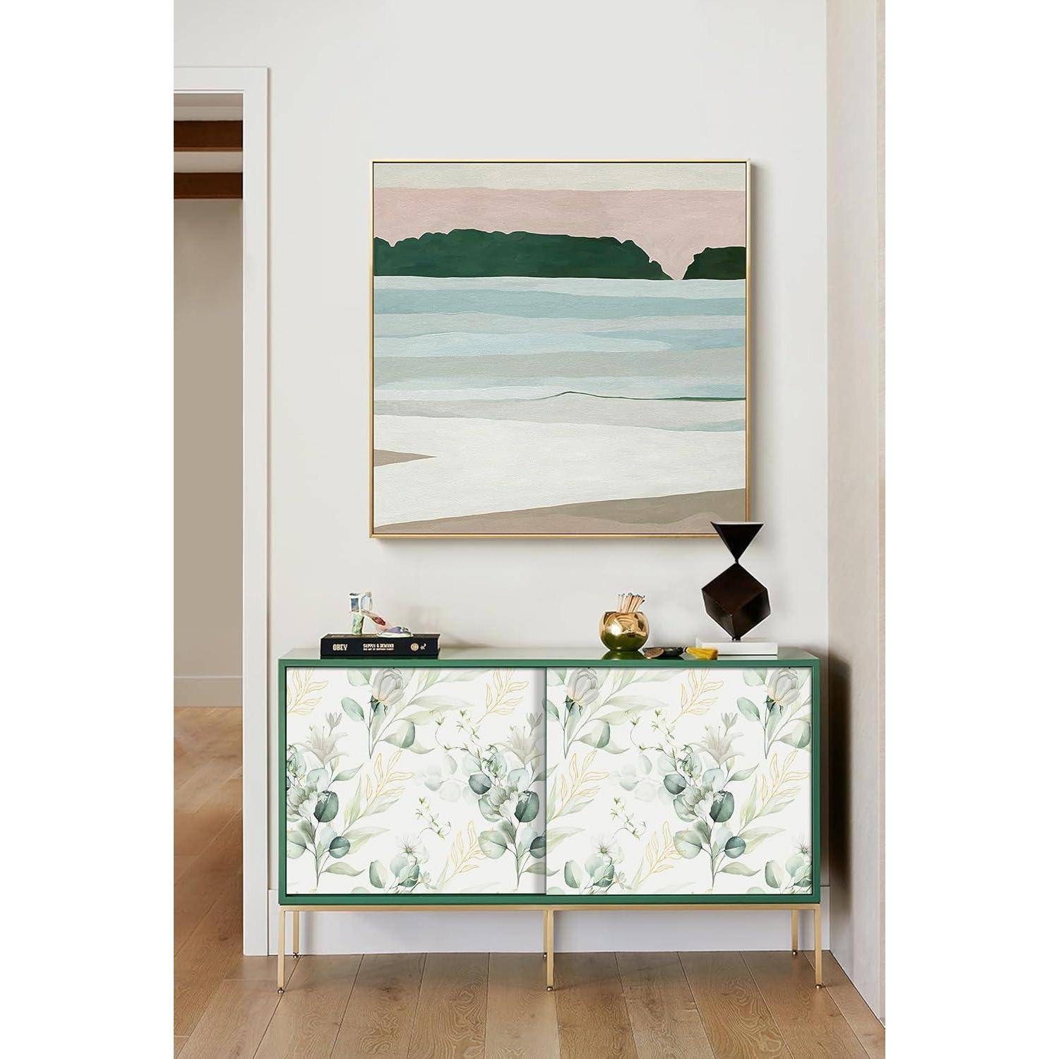 Ein Raum mit einem modernen Sideboard, das ein Blumenmuster aufweist und mit Dekorationsgegenständen verziert ist. Darüber hängt ein Landschaftsgemälde, das eine ruhige Note hinzufügt.