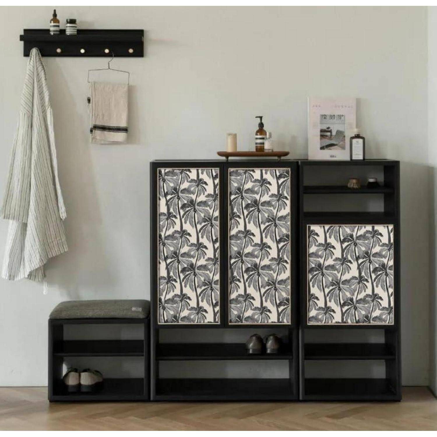 Ein moderner Eingangsbereich präsentiert einen schwarzen Holzschuhschrank mit Türen im tropischen Blättermuster, eine kleine Bank und eine wandmontierte Garderobe.