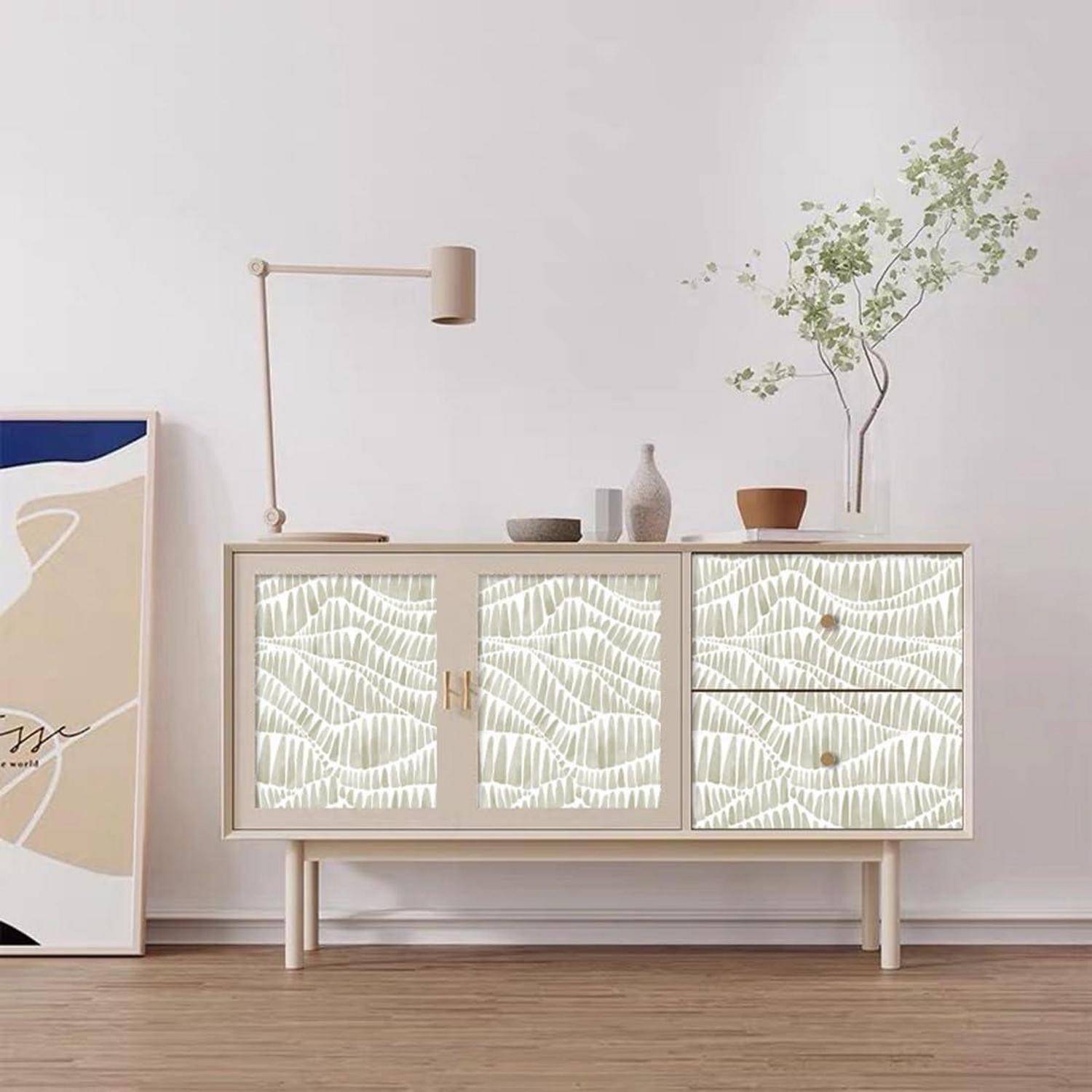 Ein moderner Wohnraum zeigt einen hellen Holzschrank mit abstraktem Design, eine wandmontierte Lampe und eine Topfpflanze auf der Oberfläche.