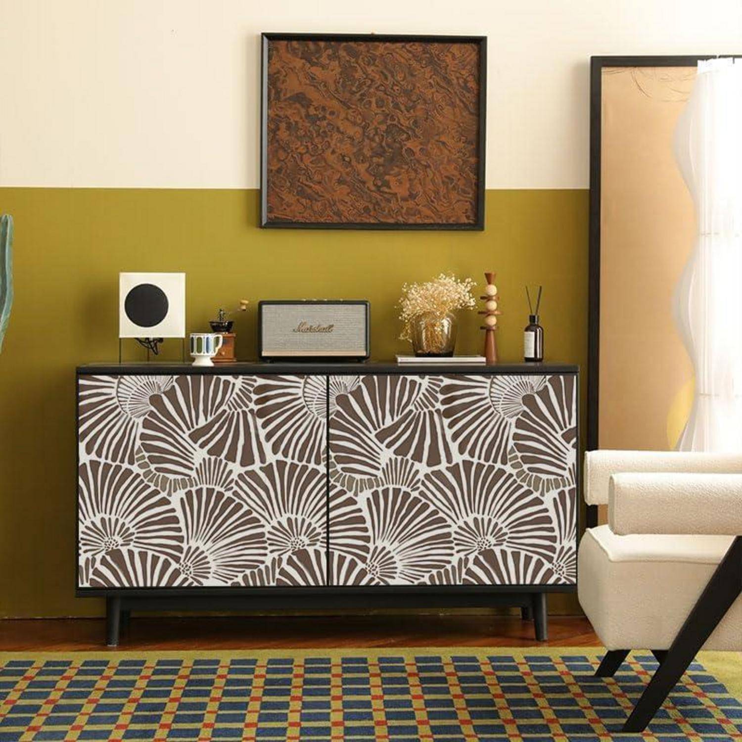 Ein stilvolles Wohnzimmer mit einem gemusterten Sideboard, dekorativer Kunstwerken und ordentlich arrangierten Gegenständen darauf. Ein großer Spiegel steht daneben.