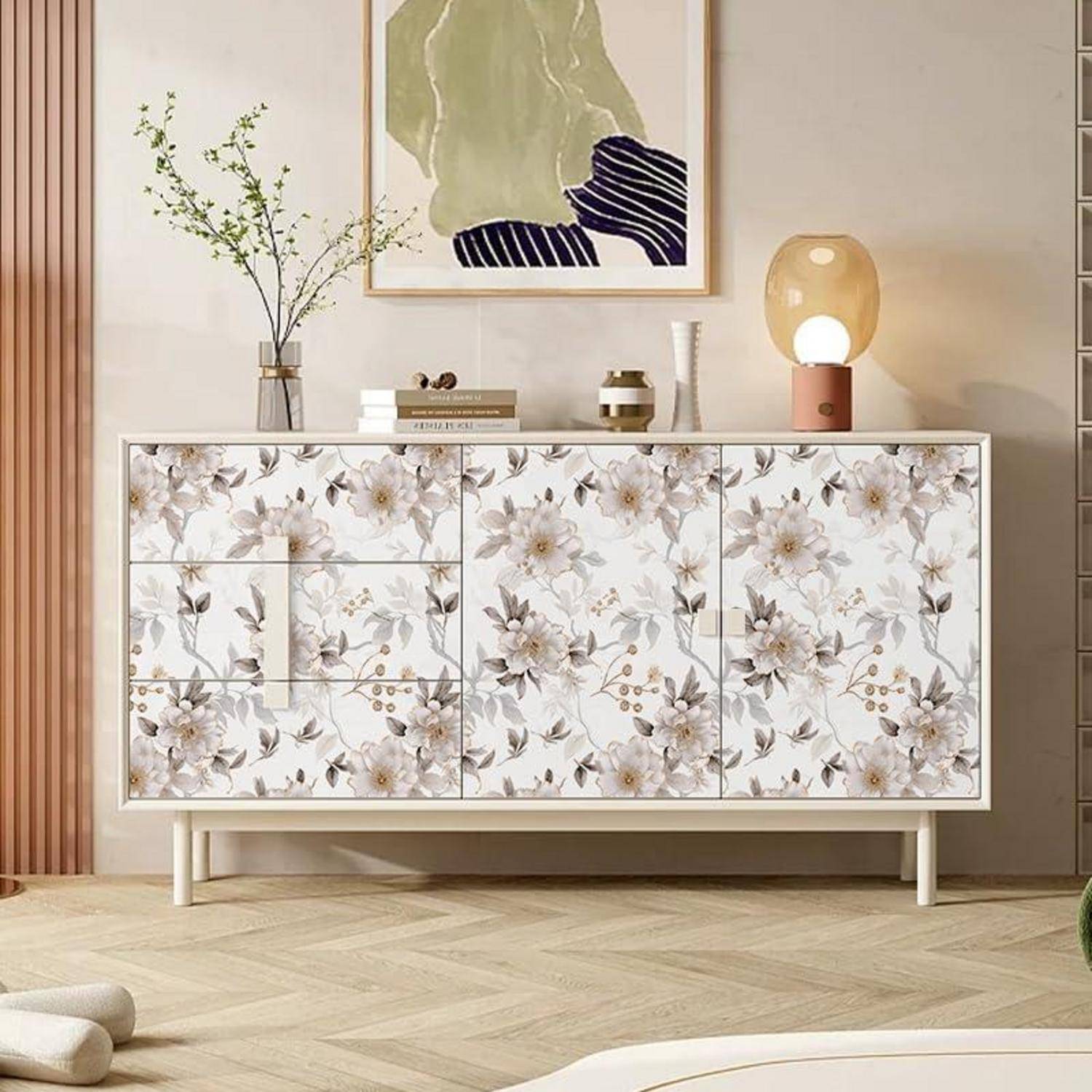 Ein blumenmustergeschmücktes Sideboard in einem modernen Wohnzimmer, geschmückt mit einem gerahmten abstrakten Kunstwerk und minimaler Dekoration obenauf, in warmem Licht getaucht.