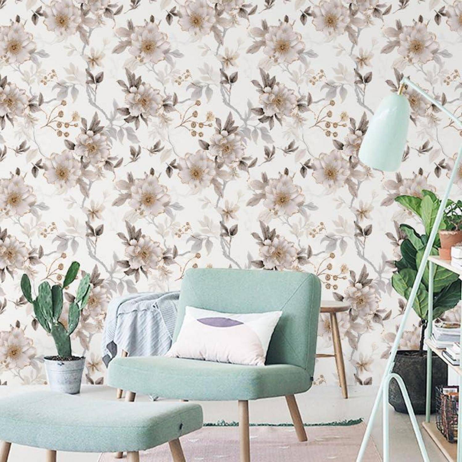 Ein gemütliches Wohnzimmer mit floraler Tapete, einem beigen Sofa mit grünen Kissen, einem kleinen Tisch und einer grünen Stehlampe.