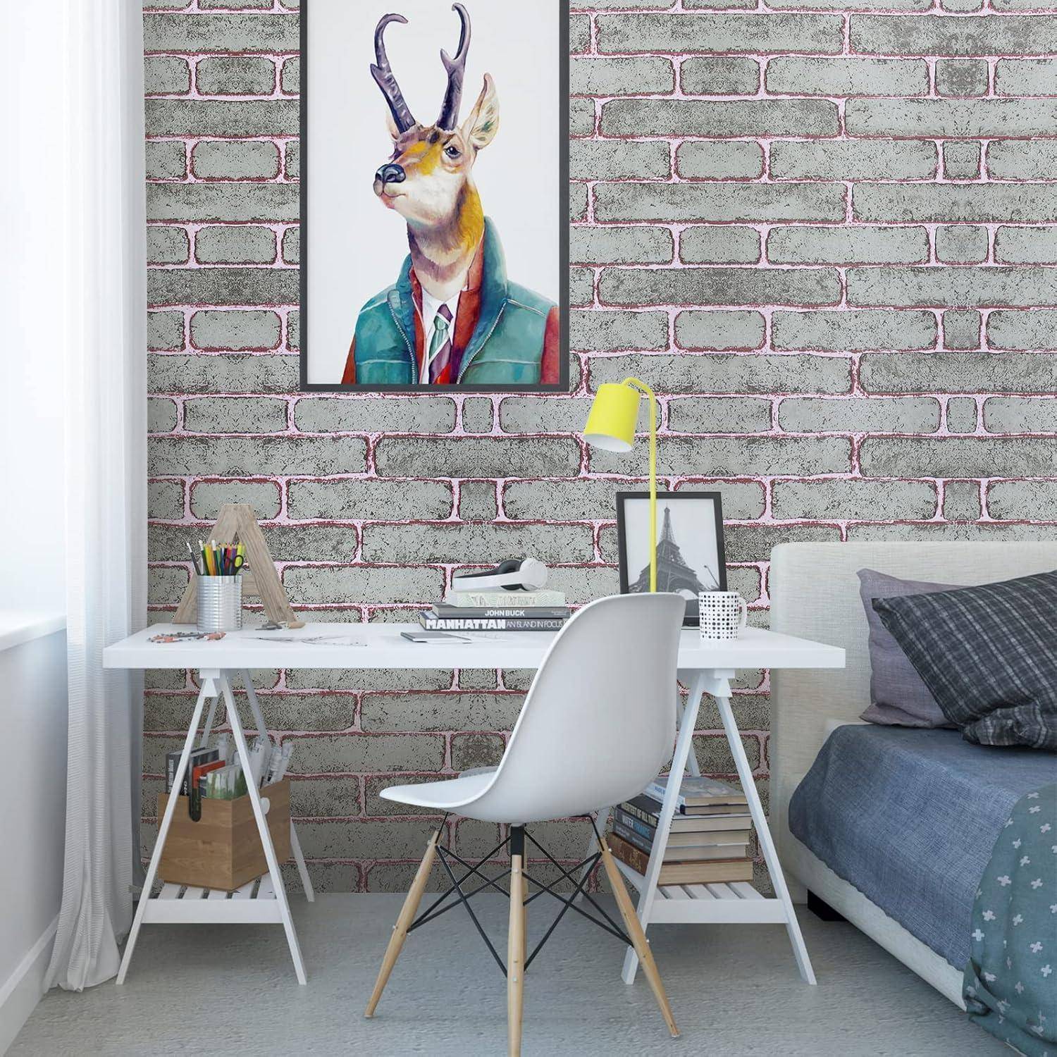 Ein modernes Zimmer mit einem Schreibtisch und einem Stuhl, an der Ziegelwand hängt gerahmte Kunstwerke mit einem aufgebrezten Hirsch. Ein Bett und eine Lampe befinden sich in der Nähe.