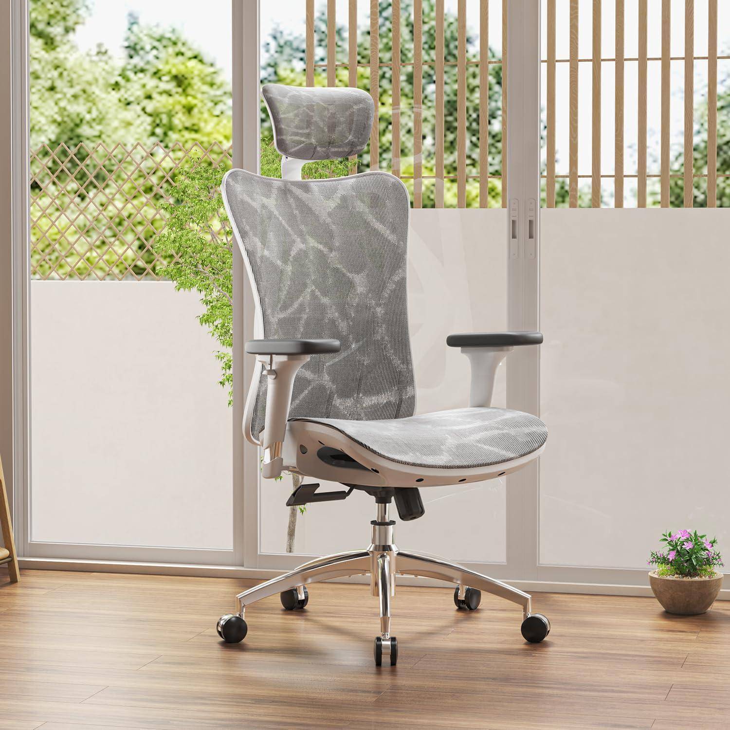 Ergonomischer Bürostuhl mit Lendenwirbelstütze vor Glastüren mit Blick auf einen Gartenbereich im Hintergrund.