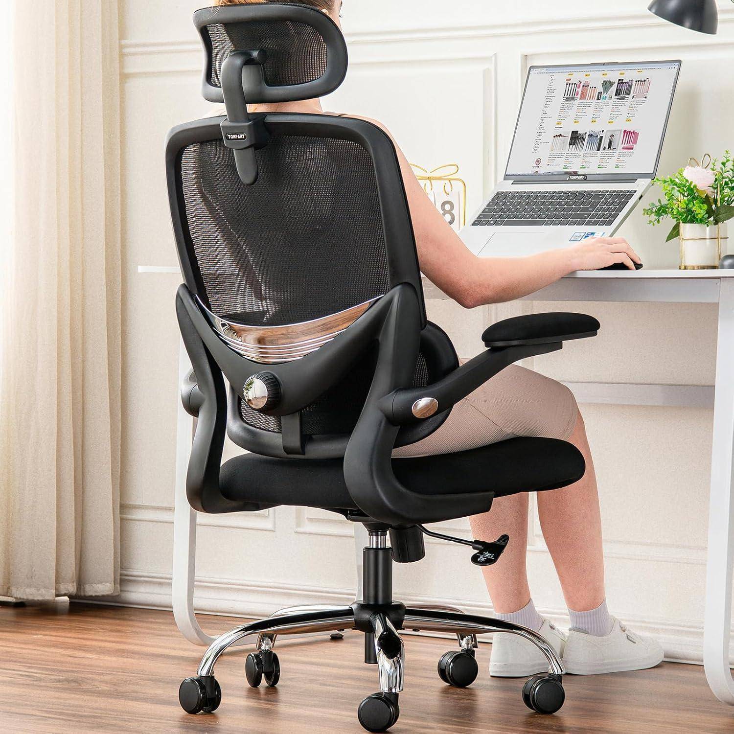 Eine Person, die in einem ergonomischen Stuhl sitzt und an einem Laptop an einem Schreibtisch arbeitet. Der Stuhl hat eine hohe Rückenlehne und eine Lordosenstütze.