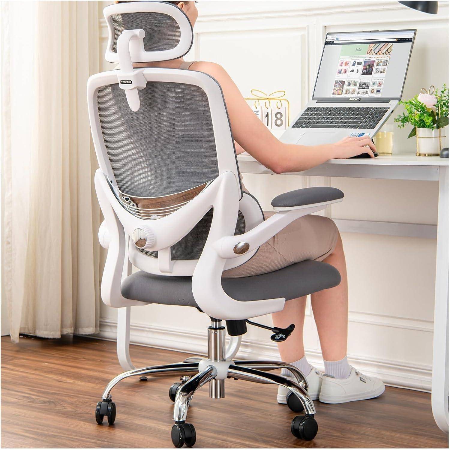 Eine Person, die in einem ergonomischen Bürostuhl sitzt und einen Laptop auf einem Schreibtisch verwendet, was eine komfortable Arbeitsumgebung im Homeoffice andeutet.