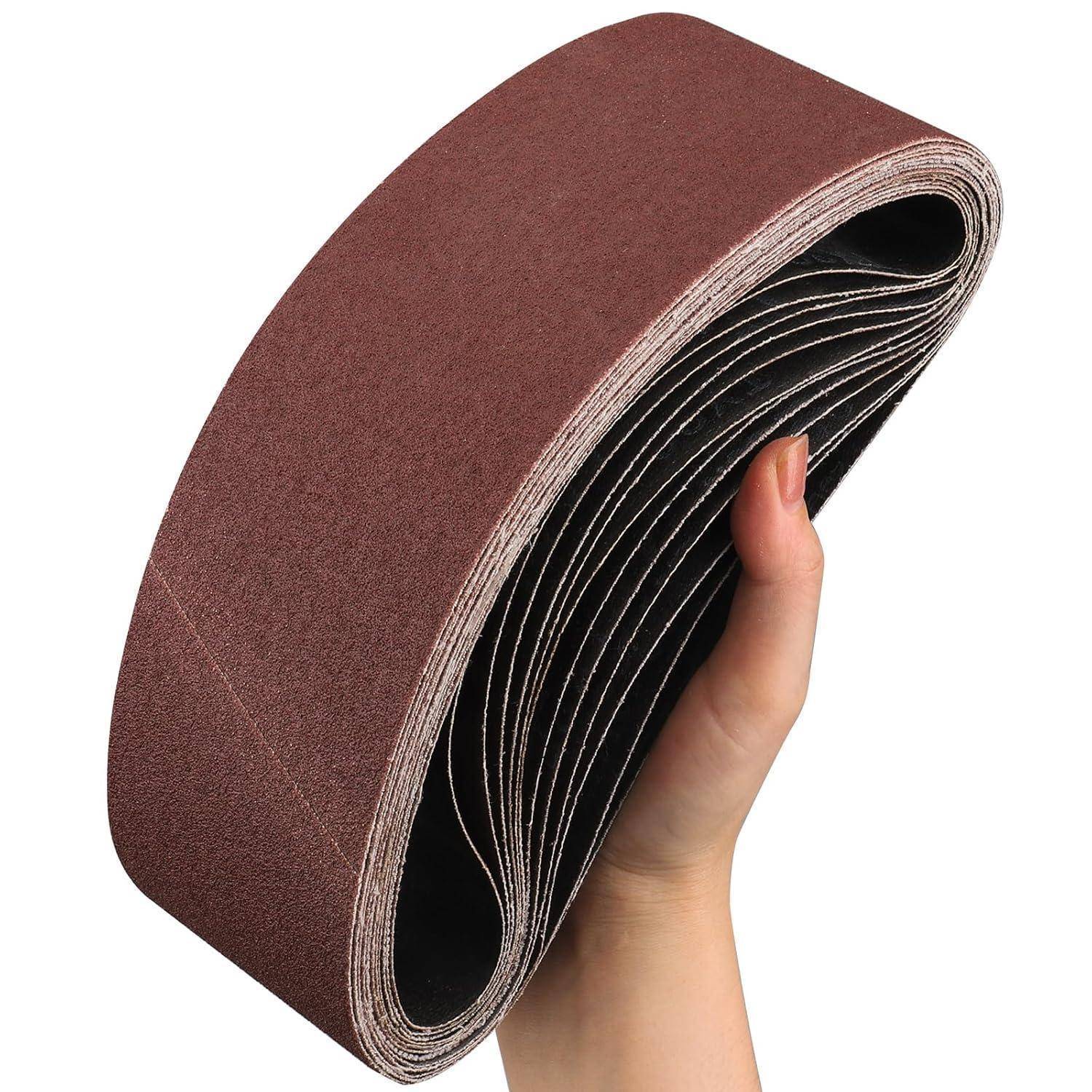 Eine Hand hält eine Rolle von braunen Schleifbändern, die zum Schleifen von Oberflächen verwendet werden.
