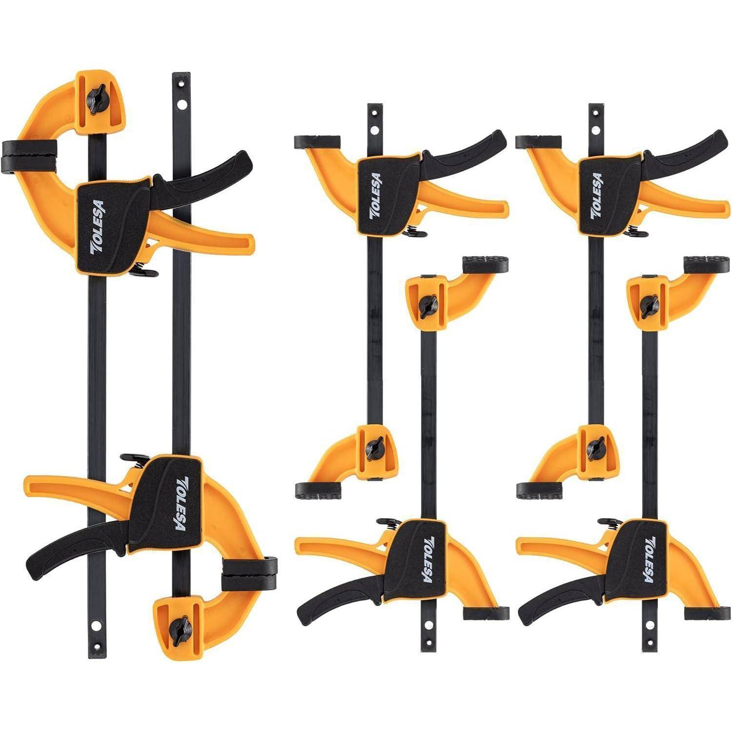 Sechs orange und schwarze Klammern sind in einem Gitterraster angeordnet und für Holz- oder Metallarbeiten konzipiert, um Materialien sicher zu befestigen.