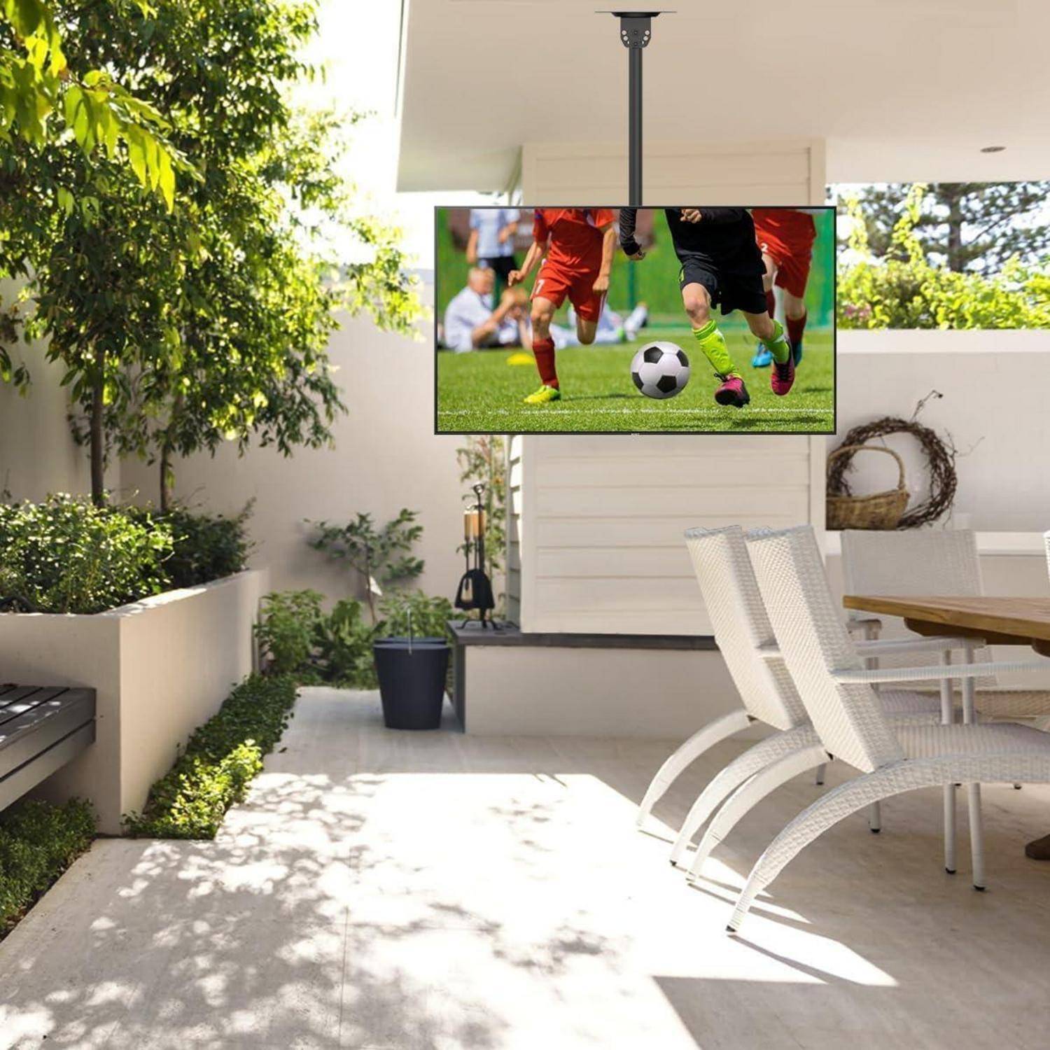 Außenbereich einer Terrasse mit einem großen Fernseher, auf dem ein Fußballspiel übertragen wird. Moderne Möbel, Grünpflanzen und sanfte Beleuchtung schaffen eine entspannende Atmosphäre.