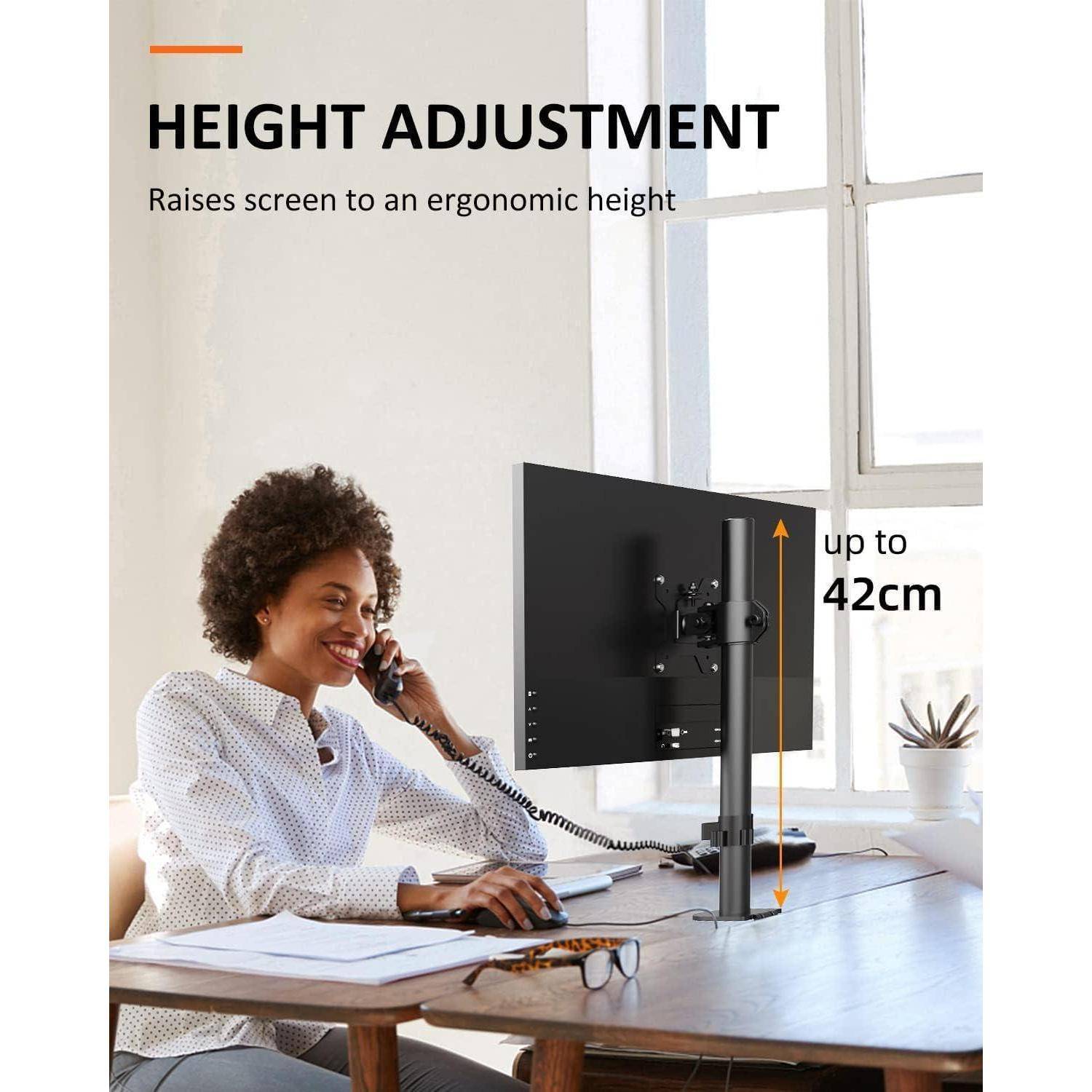 Eine Person am Telefon an einem Schreibtisch, mit einem Monitorständer, der die Bildschirmhöhe bis zu 42 cm für ergonomische Nutzung verstellen kann, in der Nähe eines Fensters.