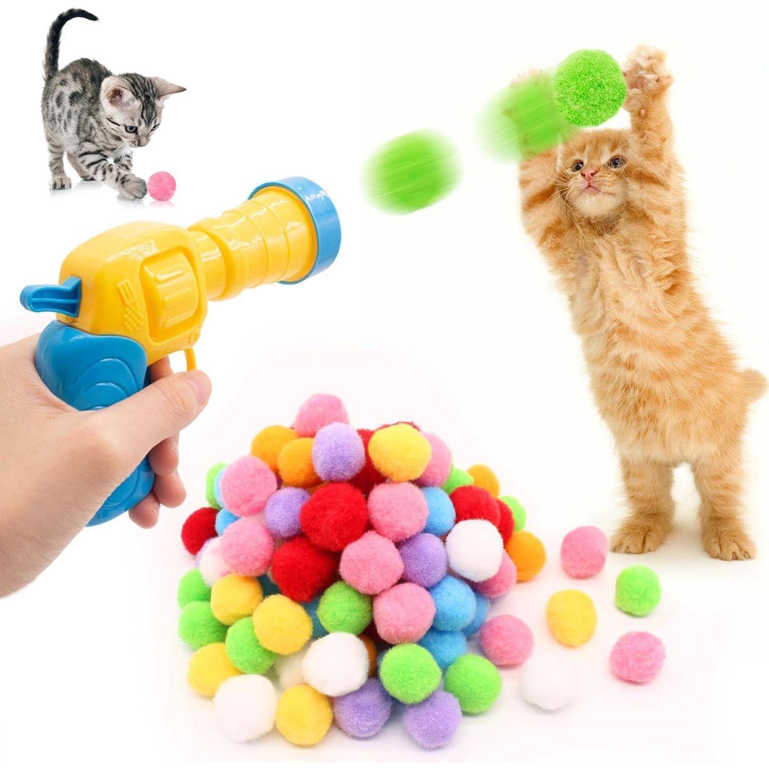 Eine verspieltes Kätzchen springt, um bunte Bälle zu fangen, während eine Hand eine Spielzeug-Ballkanone hält. Ein Haufen bunter Bälle liegt im Vordergrund.