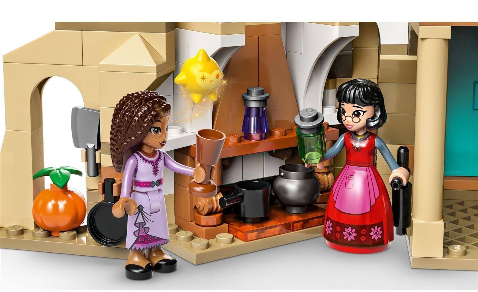 Zwei LEGO-ähnliche Figuren stehen in einem küchsenähnlichen Raum mit einem Herd, Töpfen, einer Laterne, Obst und einer orangefarbenen Kreatur, was eine Szene zum Kochen oder Brauen von Tränken andeutet.