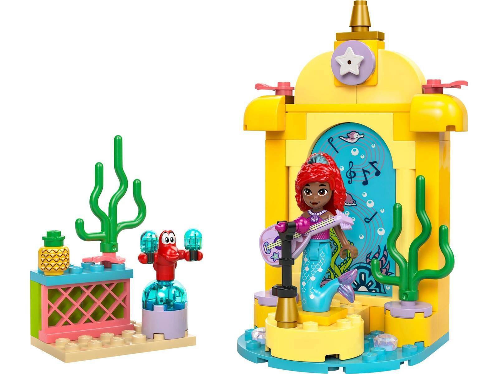 Bunter Spielzeug-Baustein-Set mit einer rothaarigen Meerjungfrau, die eine Gitarre auf einer gelben Unterwasser-Bühne spielt, mit nahegelegenen Korallen und Seepflanzen.