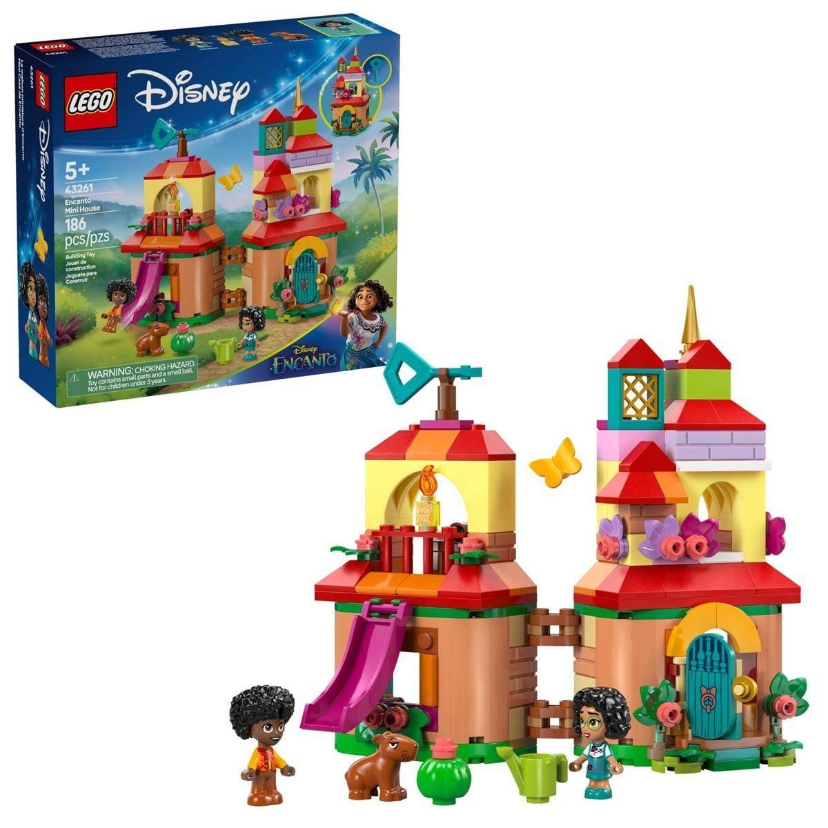 LEGO Disney Encanto Bauset mit zwei farbenfrohen Häusern, Charakteren, einem Esel und einem Schmetterling, plus die Produktschachtel in der Ecke gezeigt.