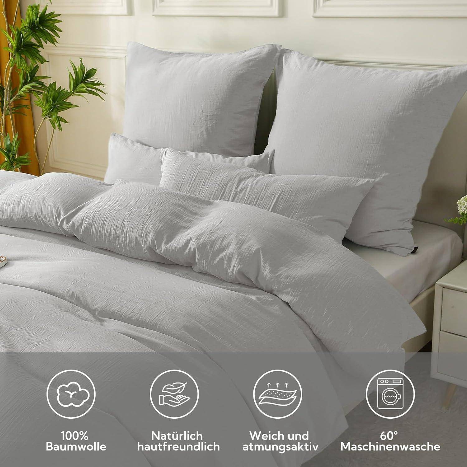 Ein sauber gemachtes Bett mit weißer Bettwäsche und Kissen in einem hellen Raum. Icons unten zeigen '100% Baumwolle', 'hautfreundlich', 'atmungsaktiv' und 'bei 60°C waschbar'.