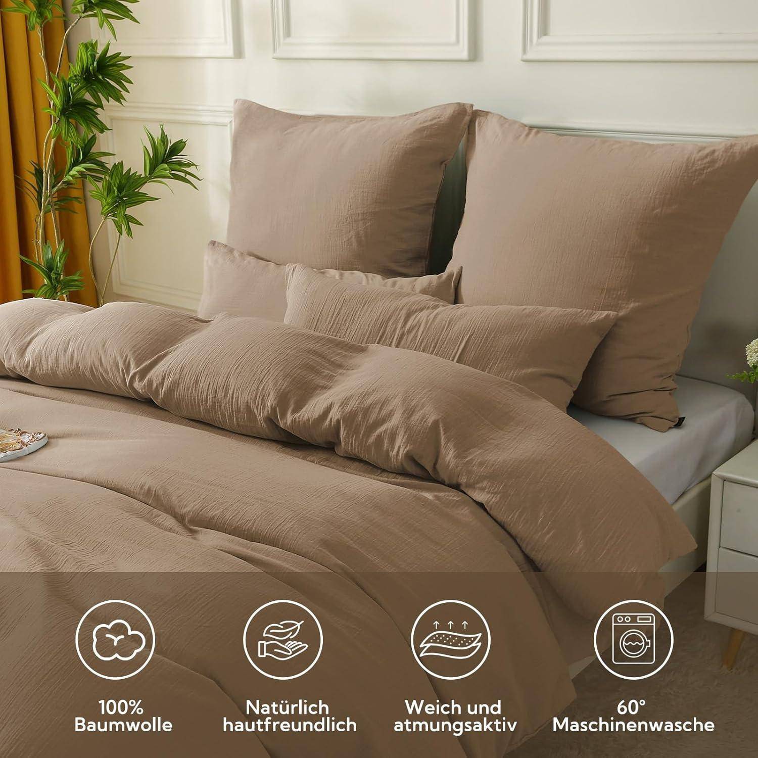 Ein ordentlich gemachtes Bett mit beigefarbener Bettwäsche steht in einem hellen Raum mit einer Pflanze in der Nähe. Icons zeigen '100% Baumwolle', 'natürlich hautfreundlich', 'atmungsaktiv' und '60° Maschinenwäsche'.