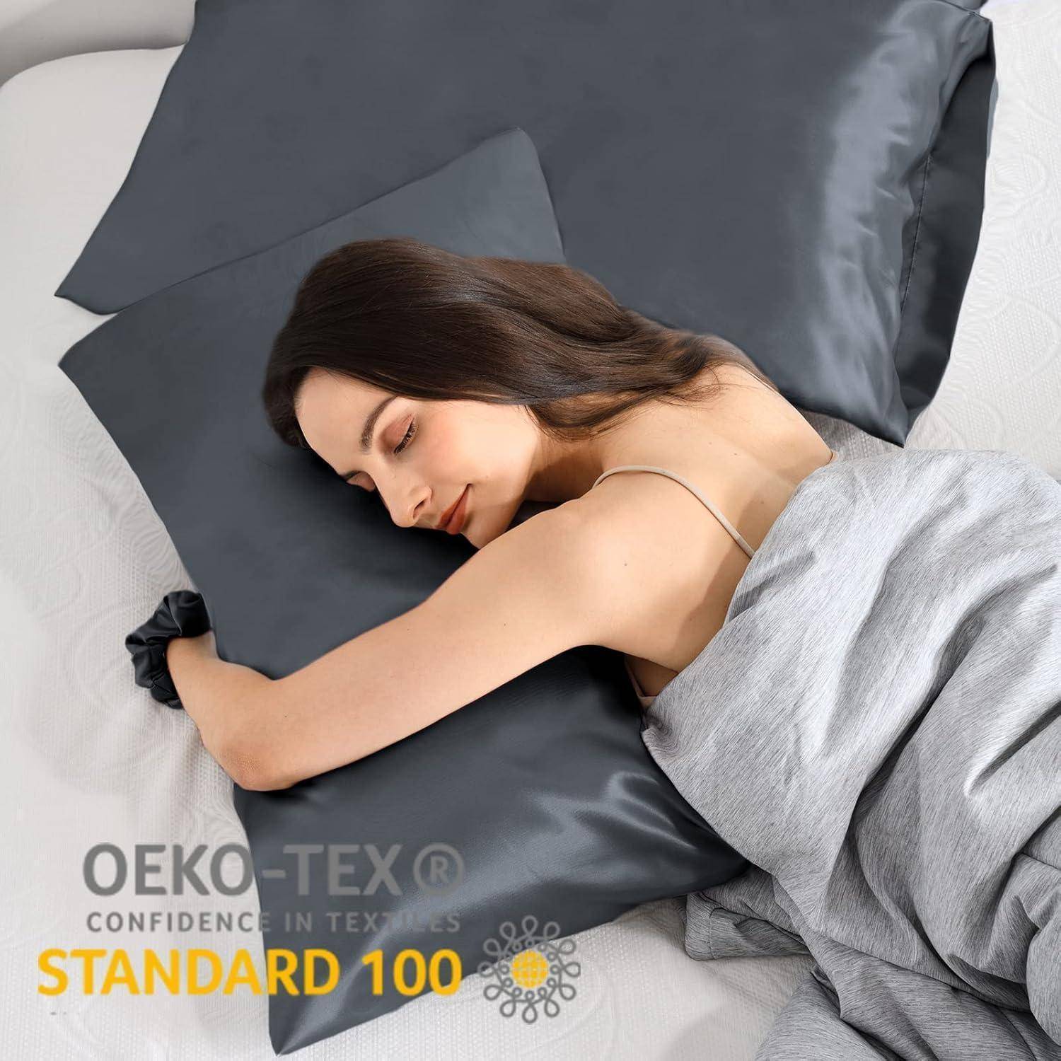 Eine Frau schläft auf einem Bett mit dunkelgrauen Kissenbezügen und einer hellgrauen Decke, die die 'OEKO-TEX Standard 100' Zertifizierung präsentiert.