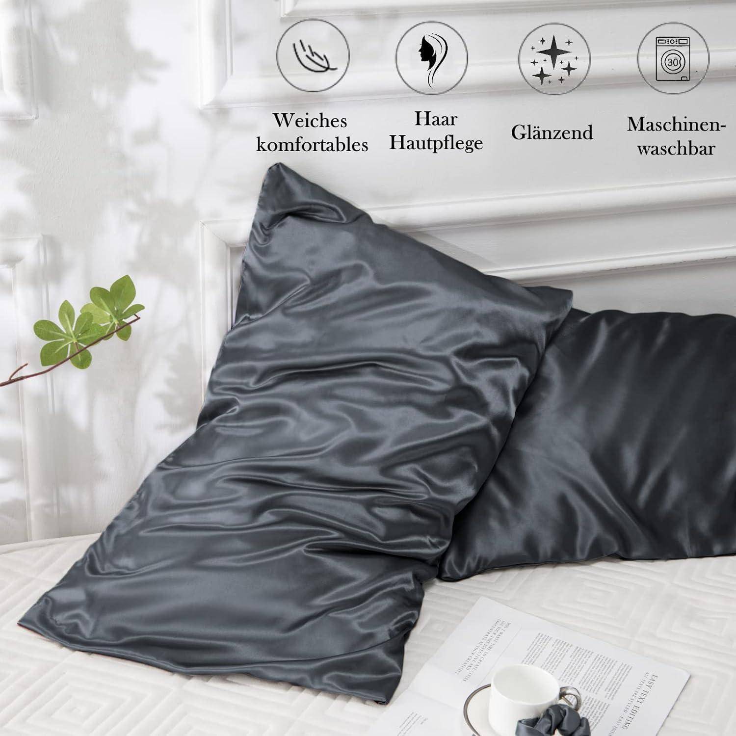 Dunkelgraue Satin-Kissenbezüge auf einem Bett, begleitet von Symbolen und deutschem Text, die Merkmale hervorheben: weiche Komfort, Haarpflege, glänzend, waschbar.