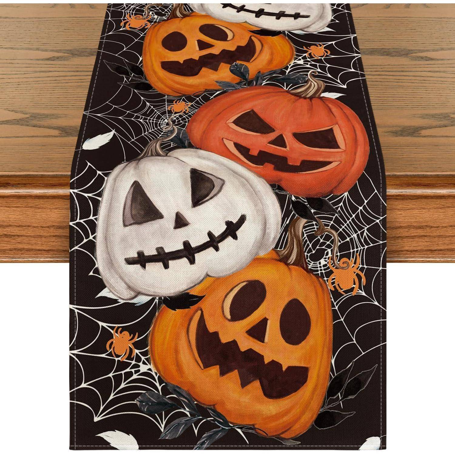 Tischläufer mit Halloween-Motiv; zeigt orangefarbene und weiße Kürbisgesichter mit Spinnennetz- und Spinnendesigns auf schwarzem Hintergrund.