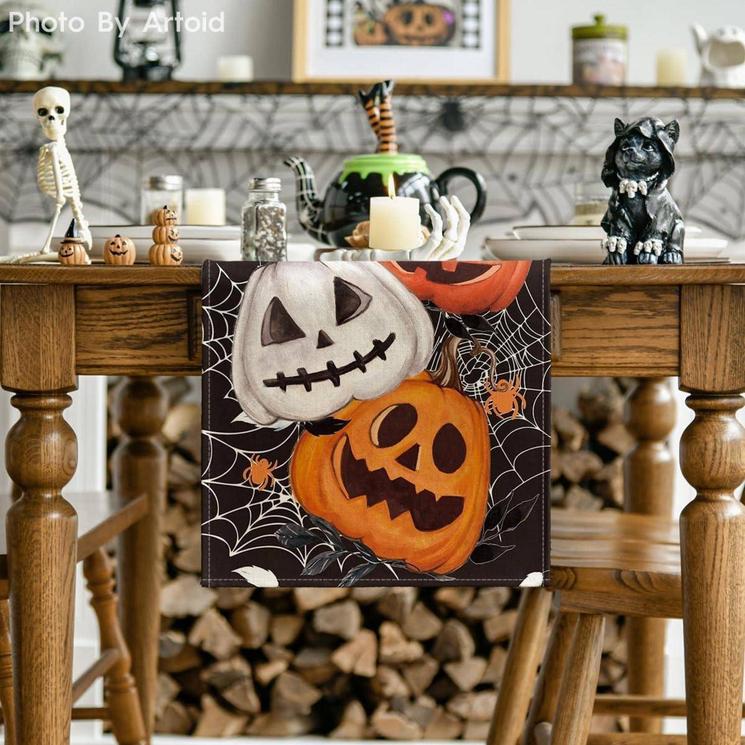 Ein Holztisch, der für Halloween dekoriert ist, mit geschnitzten Kürbissen, einem kleinen Skelett, Spinnweben und einer schwarzen Katzenfigur.