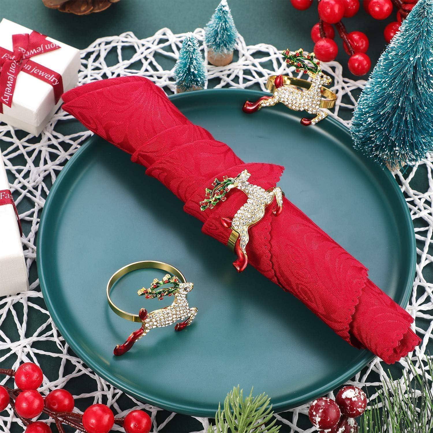 Eine festliche Tischdekoration mit einer roten Serviette, die mit dekorativen Rentieren verziert ist. Platziert auf einem dunkelgrünen Teller, umgeben von Weihnachtsschmuck.