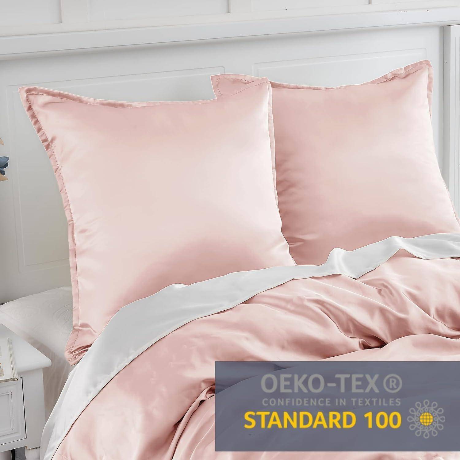 Zwei rosa Satin-Kissen und eine passende Bettdecke auf einem weißen Bett. Eingesetzt: Zertifizierungsetikett 