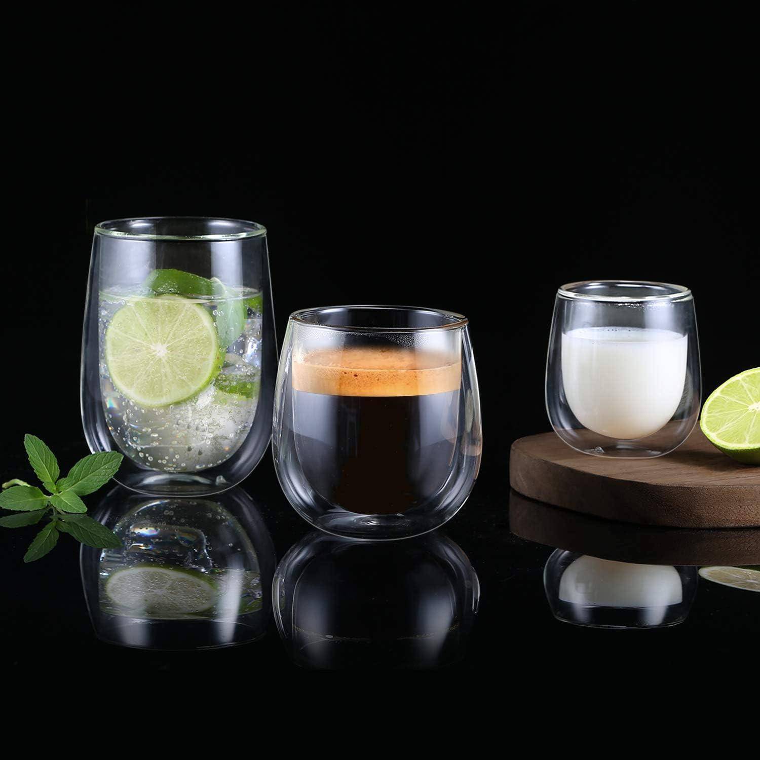 Drei Gläser auf einer reflektierenden Oberfläche: eines mit Limetten- und Minzwasser, eines mit Kaffee und eines mit Milch, begleitet von Minzblättern.