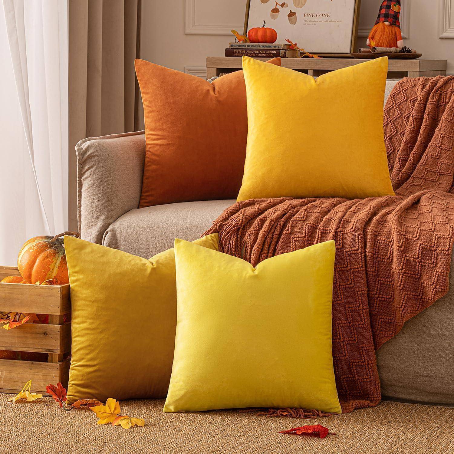 Ein herbstlich gestaltetes Wohnzimmer präsentiert ein Sofa mit orange und gelben Kissen, Kürbissen und Herbstblättern, die eine gemütliche Atmosphäre schaffen.
