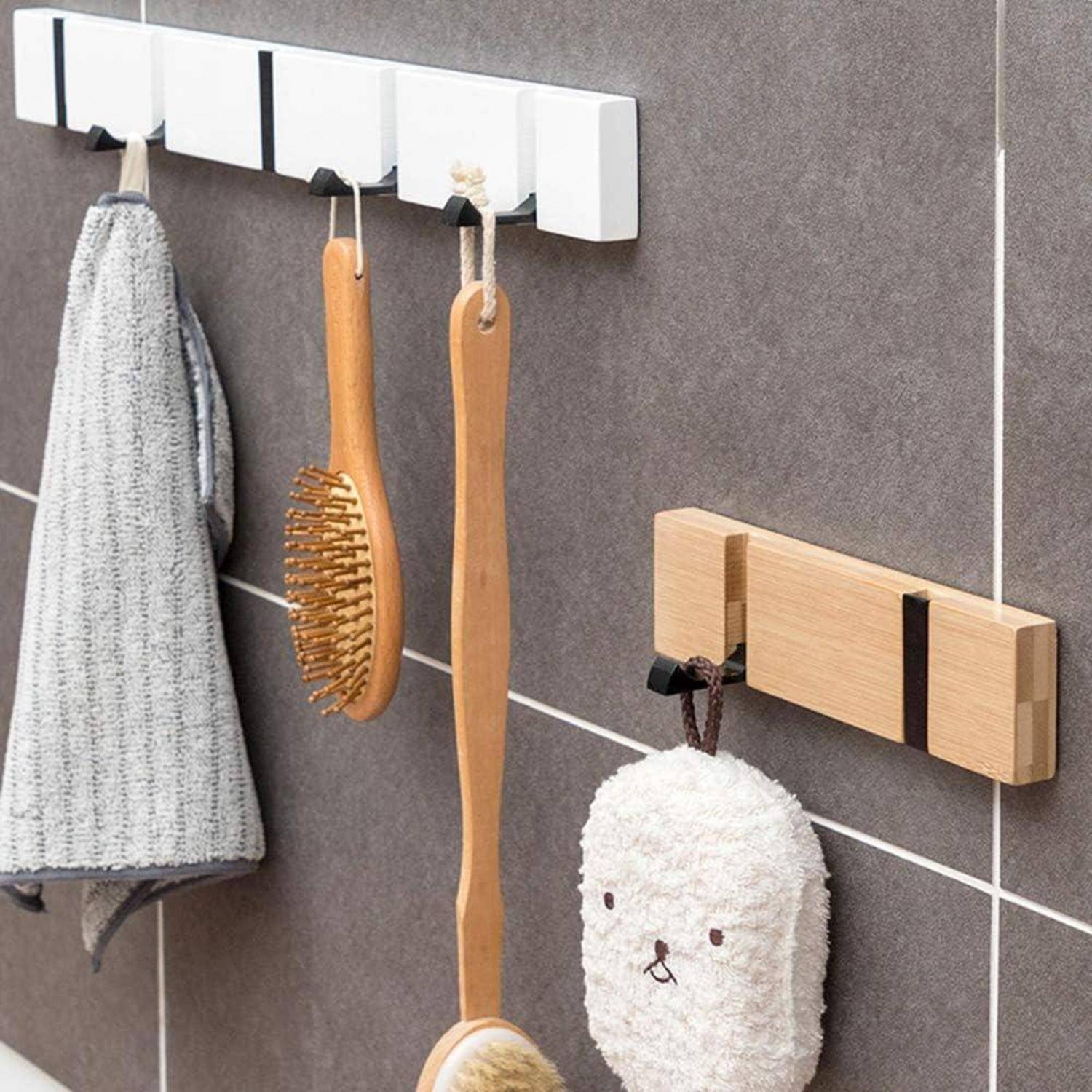 Haken an der Wand halten ein Handtuch, Holzhaarbursten und einen süßen bärchenförmigen Badeschwamm, was eine organisierte Badezimmereinrichtung zeigt.