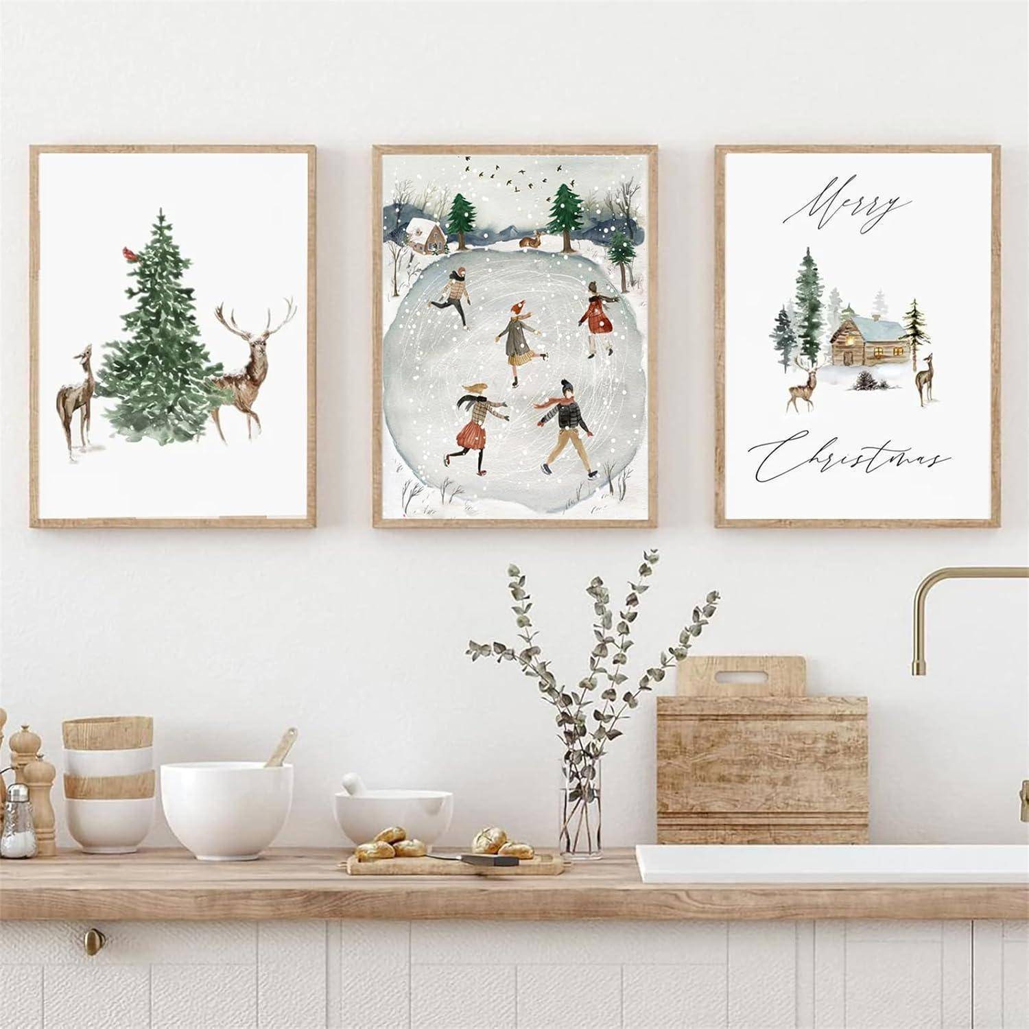 Drei gerahmte Feiertagsdrucke über einer Küchentheke: ein Hirsch neben einem Baum, Kinder beim Schlittschuhlaufen und eine Weihnachtsbotschaft mit einer Hütte.
