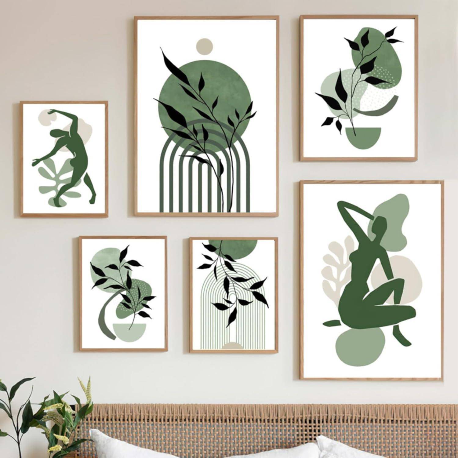 Eine Sammlung gerahmter abstrakter botanischer Kunst mit grünem und schwarzem Blattwerk an der Wand über einem Korbgeflecht-Sofa mit einer Pflanze in der Nähe.