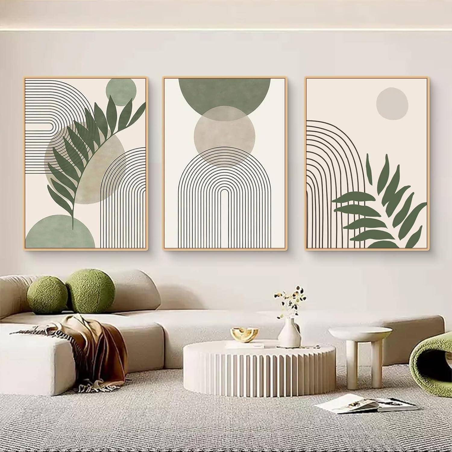 Ein moderner Wohnraum mit drei abstrakten Kunstwerken an der Wand, die geometrische Formen und natürliche Motive zeigen. Neutrale Töne dominieren die Einrichtung.