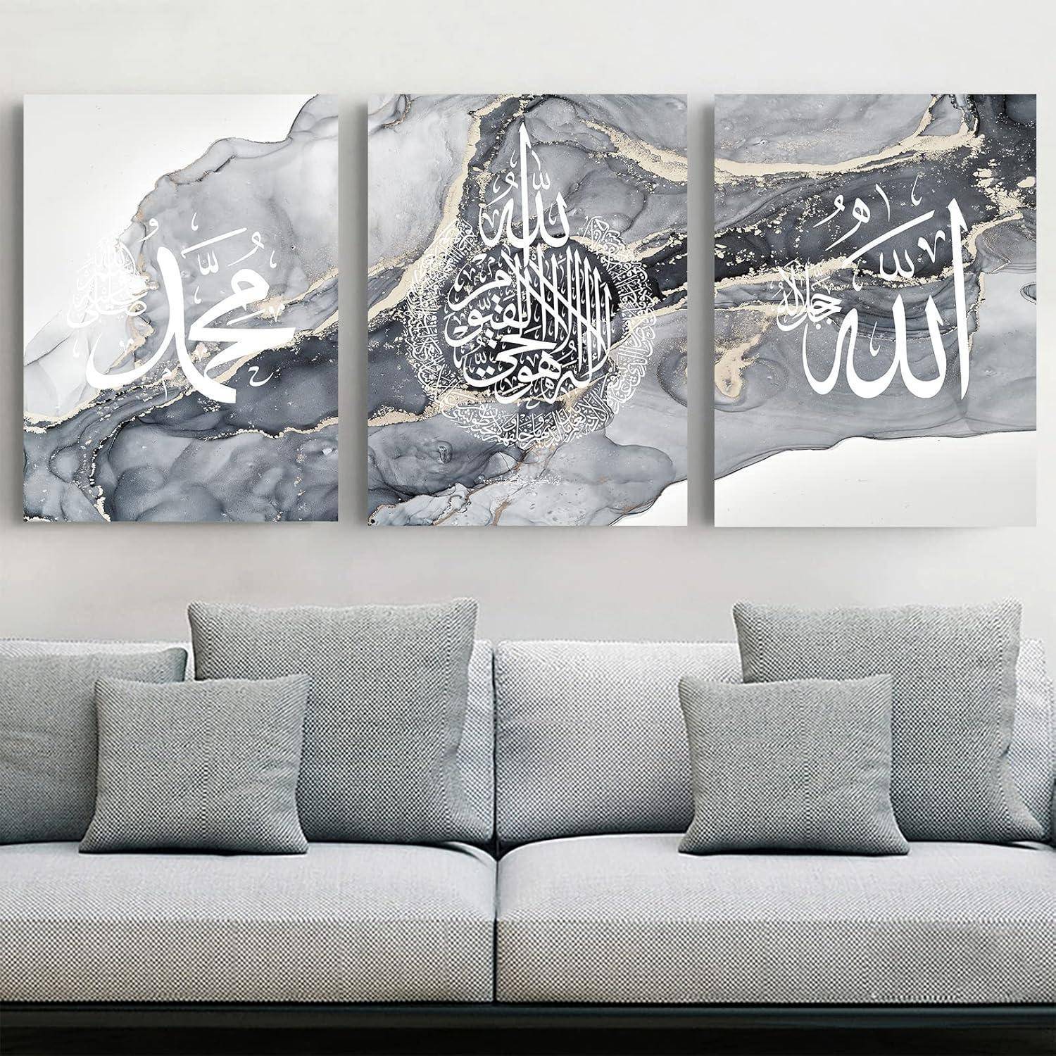 Drei dekorative Paneele über einem grauen Sofa zeigen arabische Kalligraphie in Weiß und Gold auf einem grauen Marmorhintergrund.