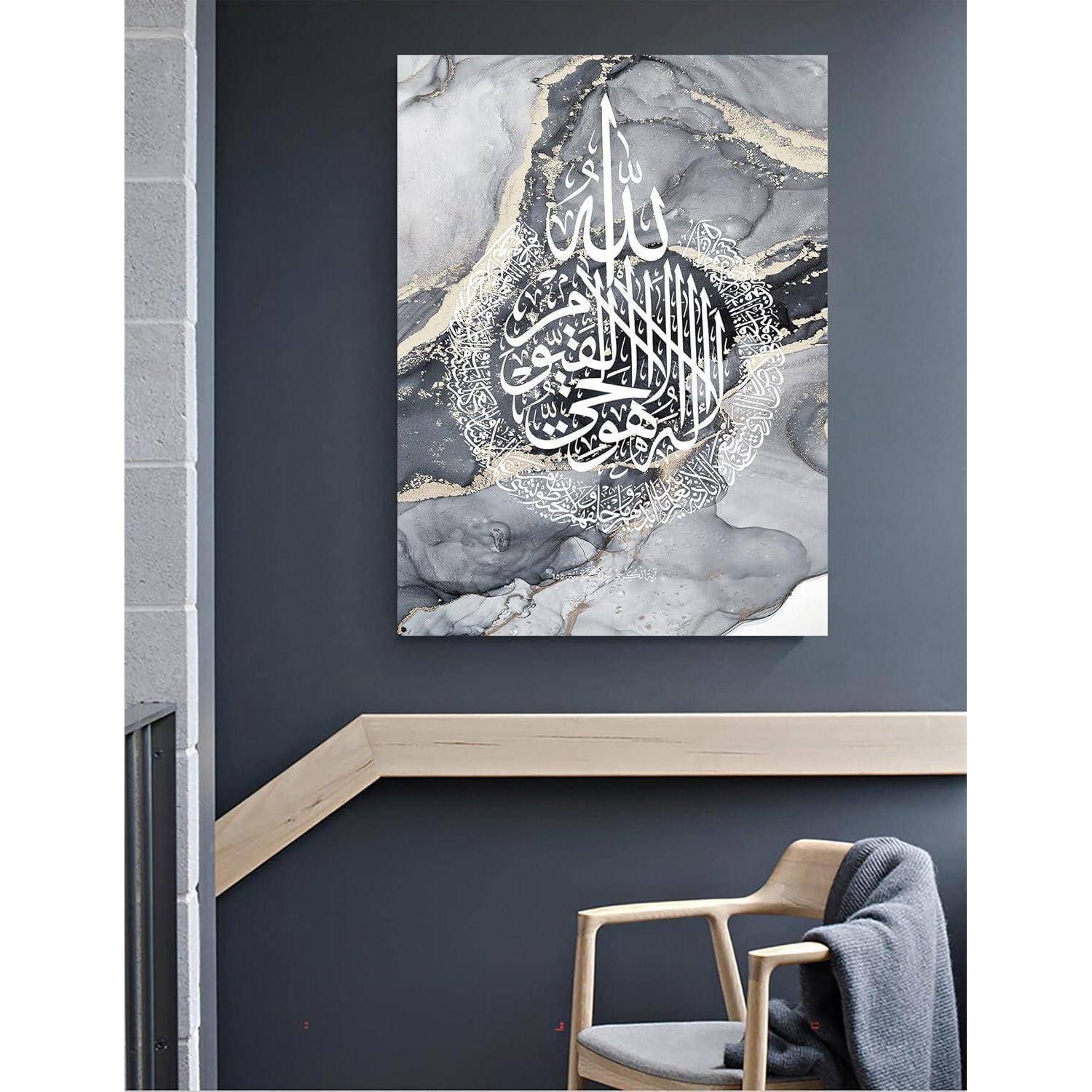 Eine Leinwand an einer dunklen Wand zeigt eine komplexe arabische Kalligraphie mit goldenen Akzenten auf einem marmorierten grauen Hintergrund. Darunter befinden sich ein Stuhl und eine Decke.