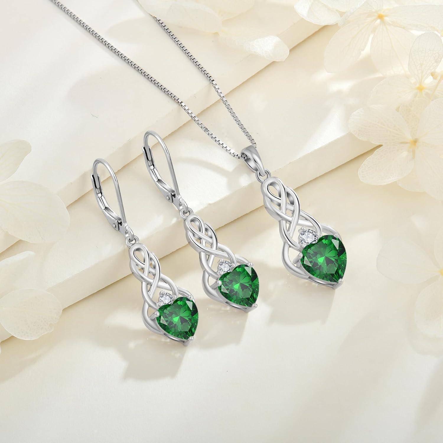 Ein Schmuckset bestehend aus einer Halskette und Ohrringen mit silbernen keltischen Knoten-Designs und herzförmigen grünen Edelsteinen, präsentiert auf einem hellen Hintergrund.