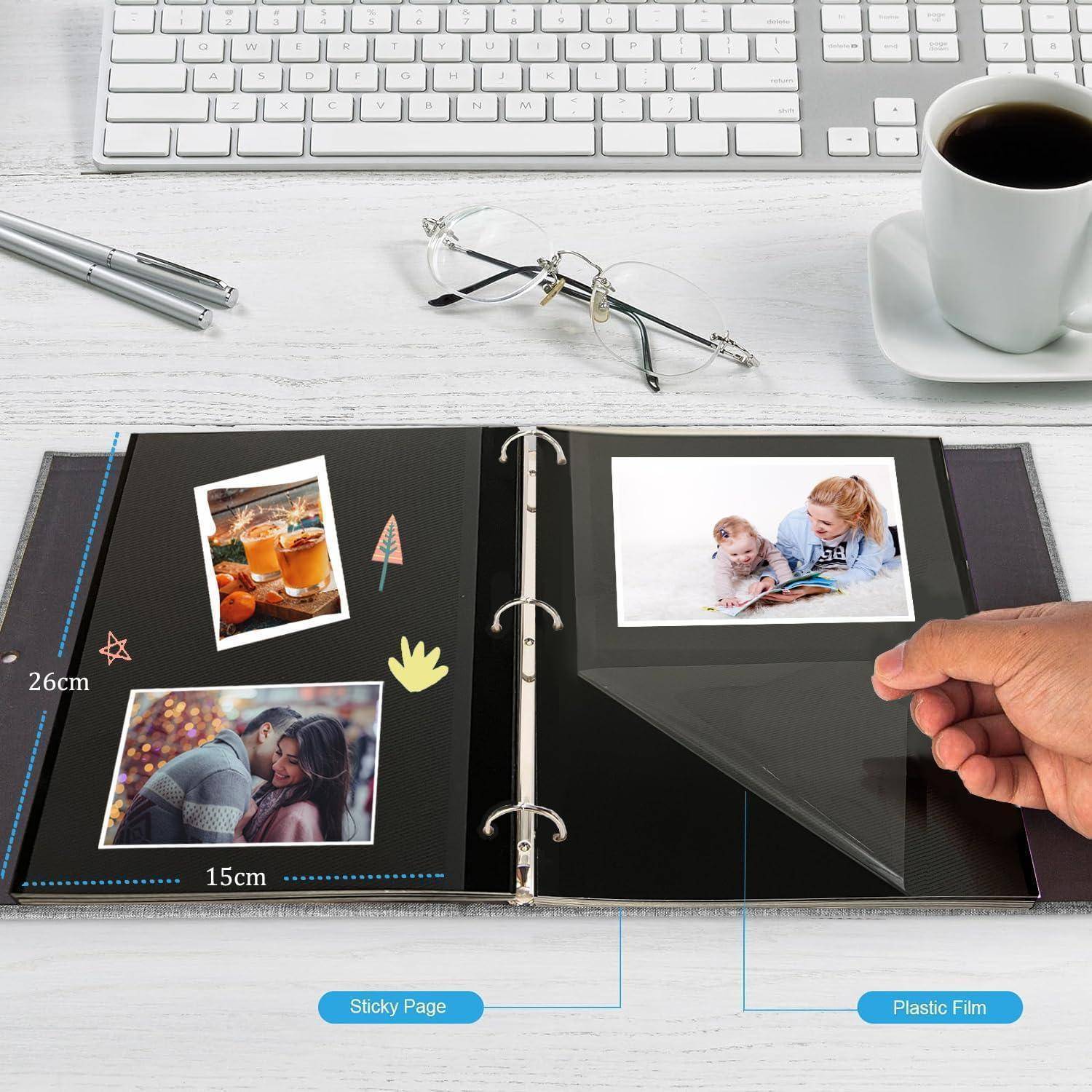 Fotoalbum auf dem Schreibtisch geöffnet mit Bildern von Familienmomenten. Eine Hand blättert eine Seite um. Brille, Tastatur, Kaffeetasse in der Nähe deuten auf eine gemütliche Umgebung hin. Maßangaben und Beschriftungen zeigen Dimensionen und Materialien an.