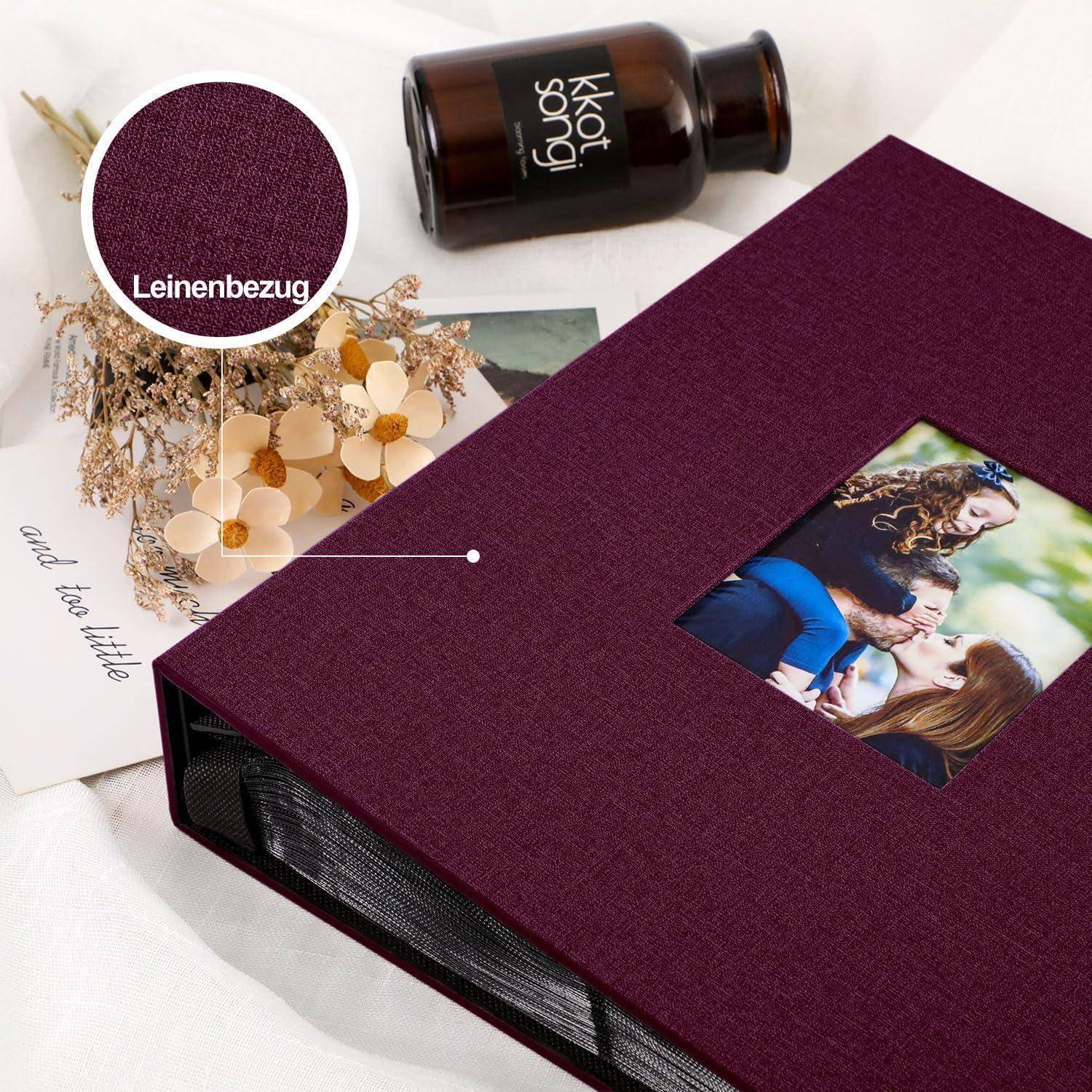 Marroner Leineneinband-Fotoalbum mit Umschlagbild von sich umarmenden Menschen; daneben Trockenblumen und schwarze Flasche auf weißem Hintergrund.