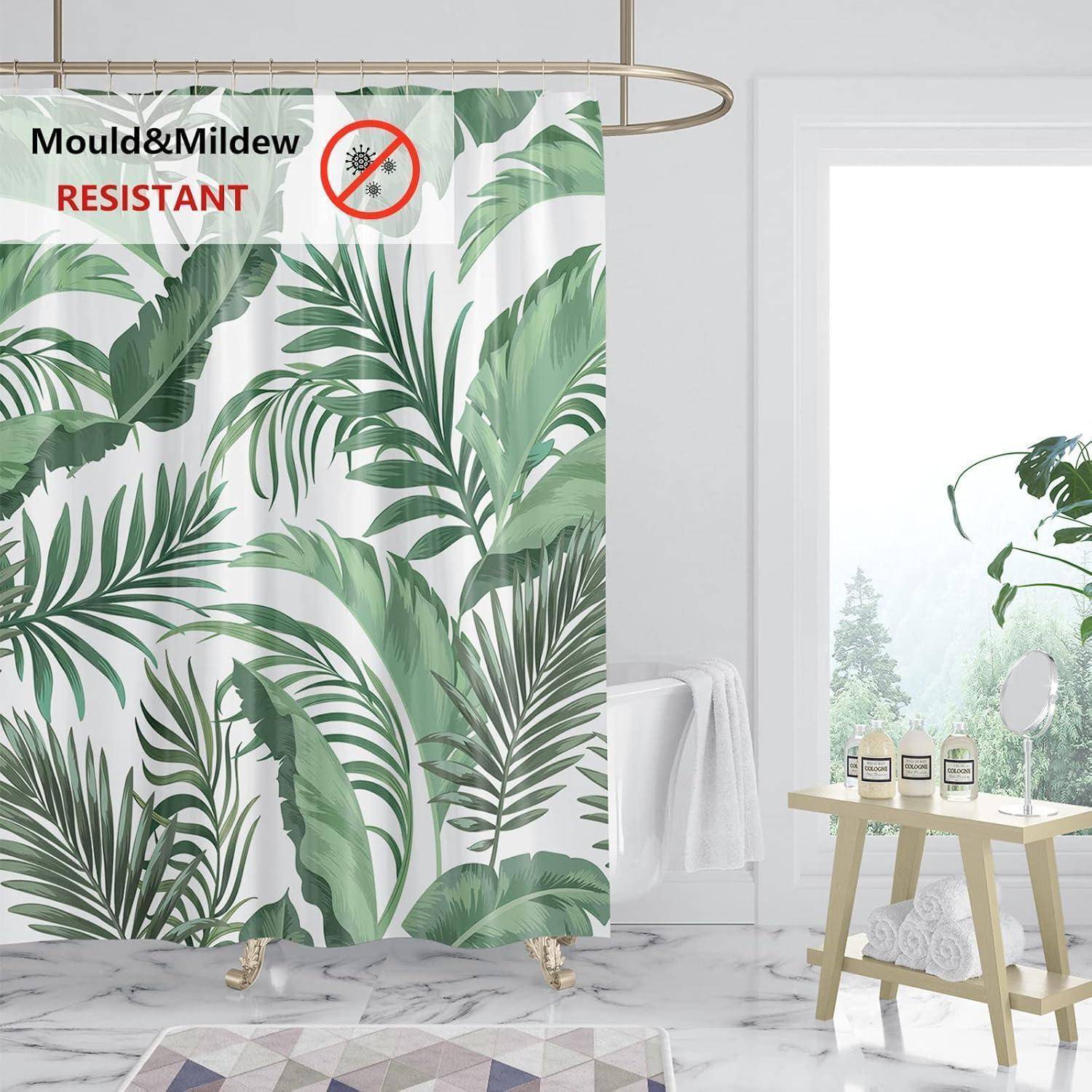 Duschvorhang mit grünem tropischem Blätterdesign in einem hellen Badezimmer. Text lautet 'Schimmel- & Schimmelpilzresistent' mit einem durchgestrichenen Schimmel-Symbol.