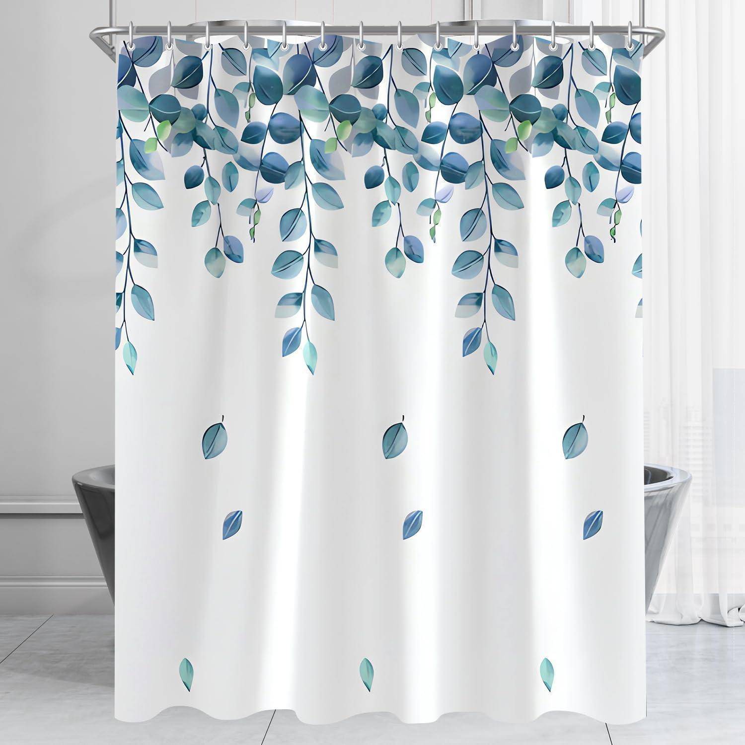 Ein Duschvorhang mit einem Muster aus blauen und grünen Blättern, die herunterhängen, in einem hellen Badezimmer mit weißen Fliesen und einer Badewanne.