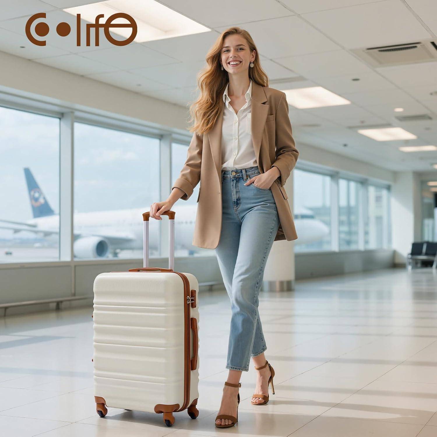 Eine Frau in einem Blazer und Jeans steht selbstbewusst in einem Flughafenkorridor und hält einen weißen Koffer, was auf eine Reise oder Geschäftsreise hindeutet.