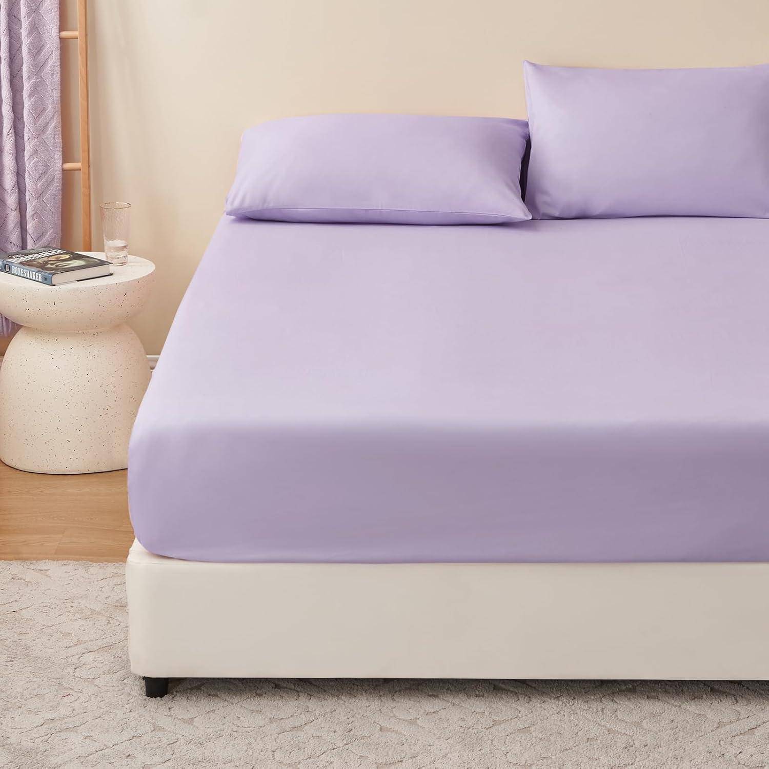 Ein ordentlich gemachtes Bett mit einem hellvioletten Laken und Kissen in einem modernen Schlafzimmer, mit einem runden Beistelltisch und Büchern in der Nähe.