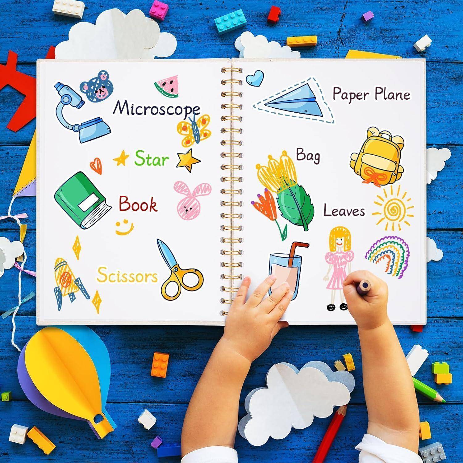 Eine Kinderhand auf einem offenen Notizbuch mit Zeichnungen, beschriftet als "Mikroskop"", ""Papierflieger"", ""Stern"", ""Tasche"", ""Buch"", ""Blätter"" und ""Schere"".