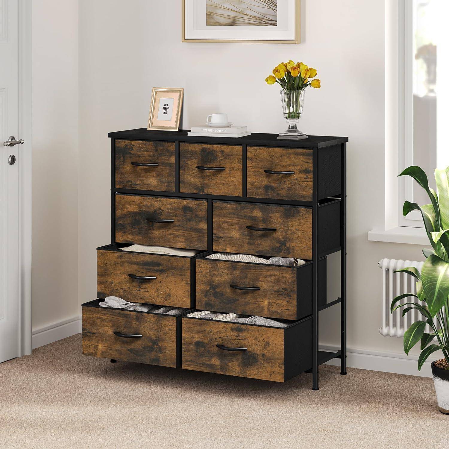 Ein hölzerner Schrank mit mehreren Schubladen, einige leicht geöffnet, steht an der Wand. Ein gerahmtes Foto und eine Vase mit gelben Blumen stehen auf der Oberfläche.