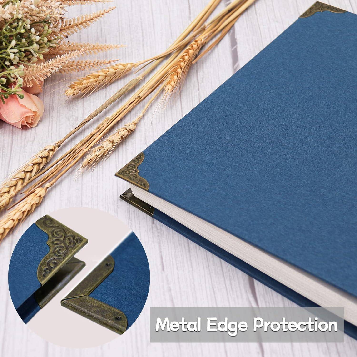 Blaues Hardcover-Buch mit dekorativen Metalleckenschutz an den Ecken, dekoriert mit getrockneten Blumen und Weizenähren auf einem hellen Holztisch.