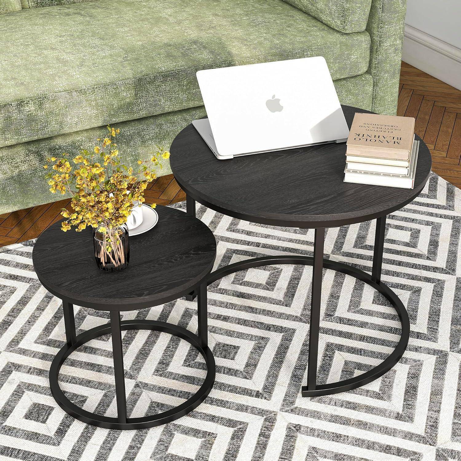 Ein kleiner schwarzer Couchtisch, bestückt mit einem Laptop, einem Buch und einer Vase mit gelben Blumen, platziert auf einem geometrisch gemusterten Teppich vor einem grünen Sofa.