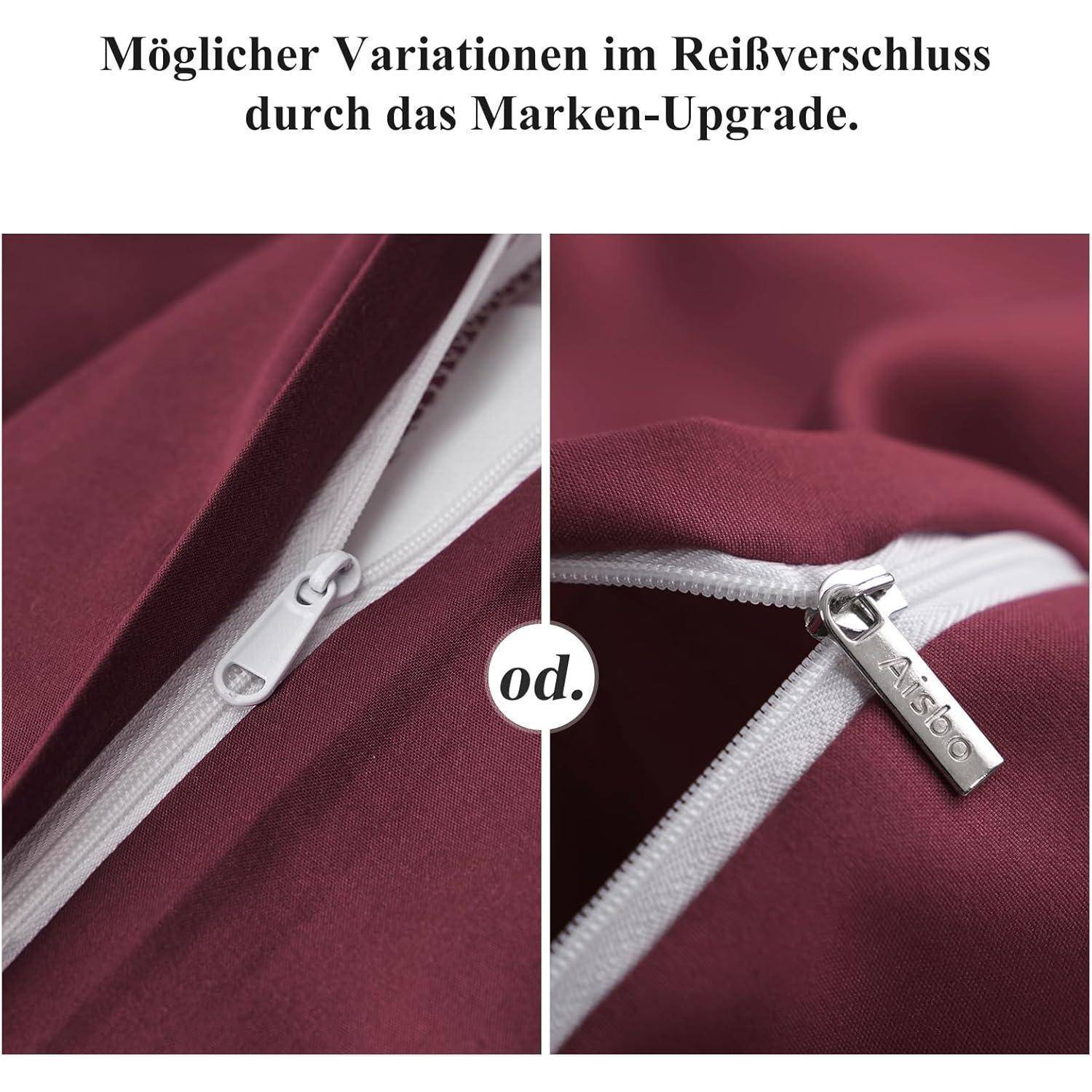 Zwei Nahaufnahmen von Reißverschlüssen auf bordeauxrotem Stoff. Ein Reißverschluss ist schlicht weiß; der andere verfügt über einen silbernen Anhänger mit der Gravur ‚Ascib'.