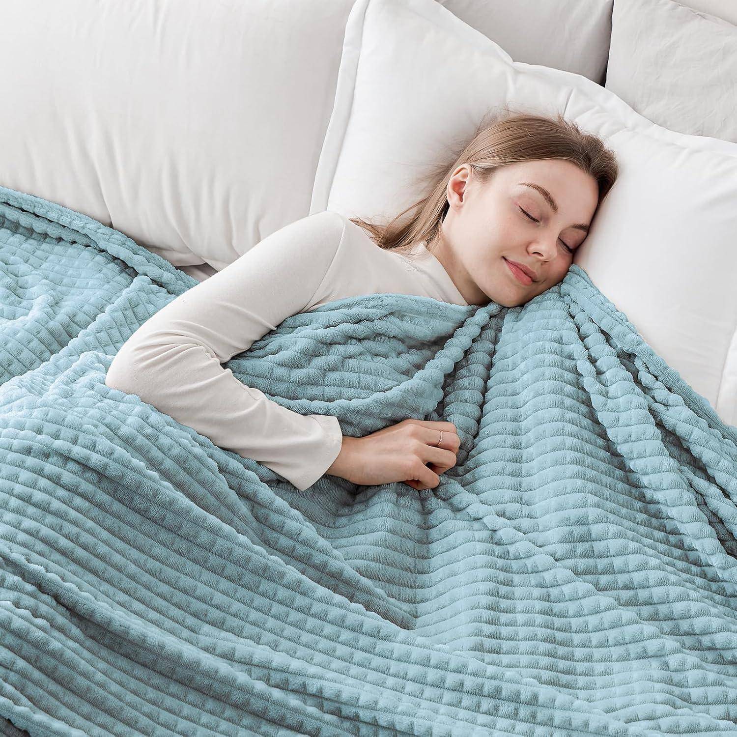 Eine Frau schläft friedlich im Bett, eingehüllt in eine weiche, hellblaue Decke mit entspanntem Gesichtsausdruck. Helle, saubere Bettwäsche umgibt sie.
